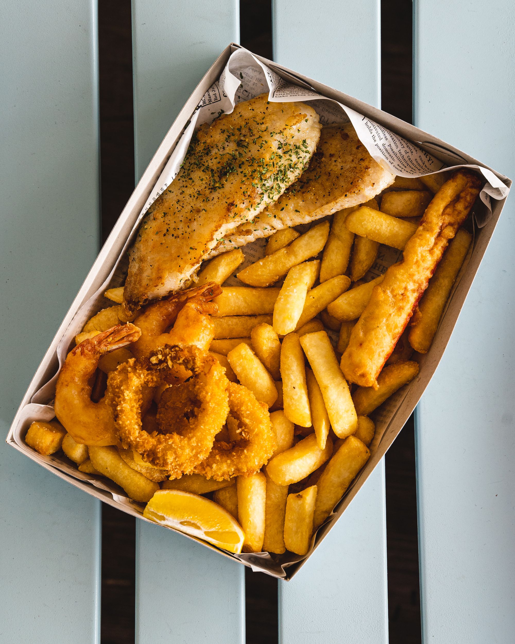 Top down shot of fish and chips in a paper box