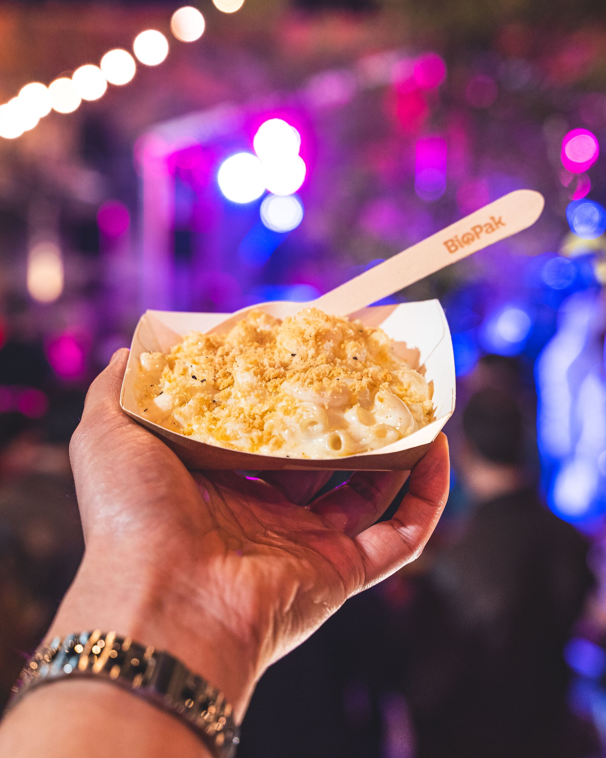 Hand holding mac and cheese in a paper plate