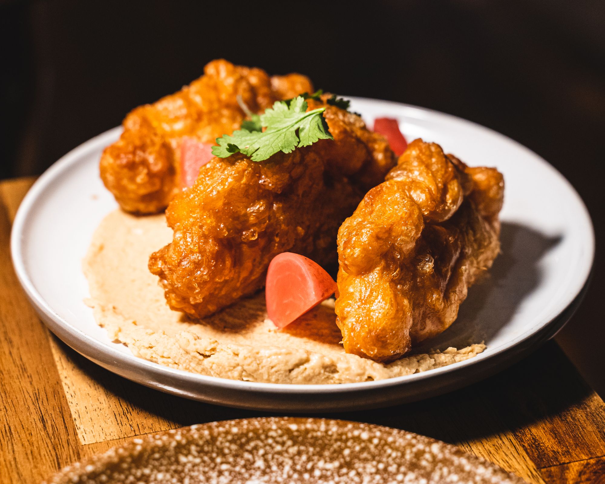 Close up of curry puffs on a layer of hummus with pickled radish