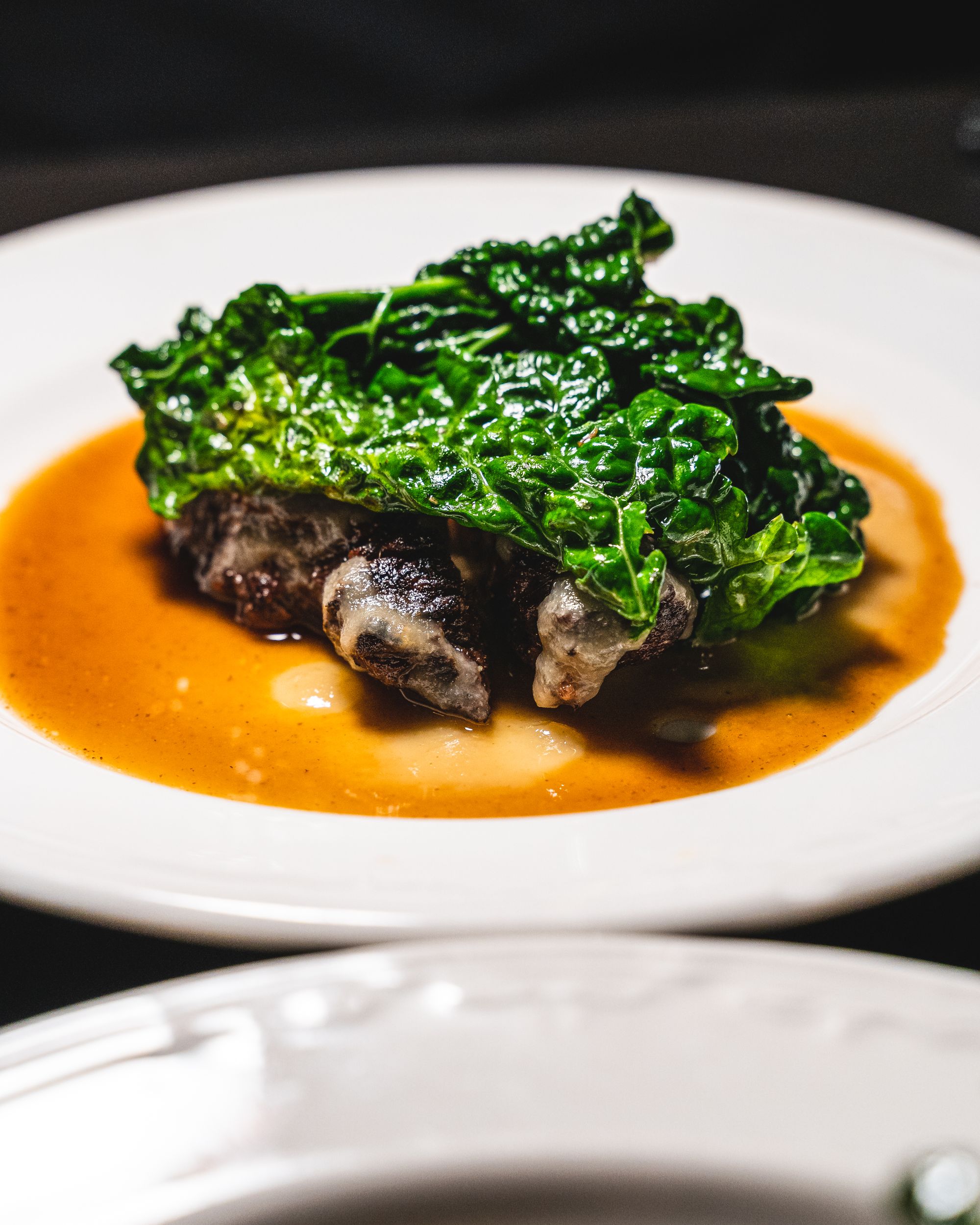 Close up of beef cheeks with a leafy vegetable on top