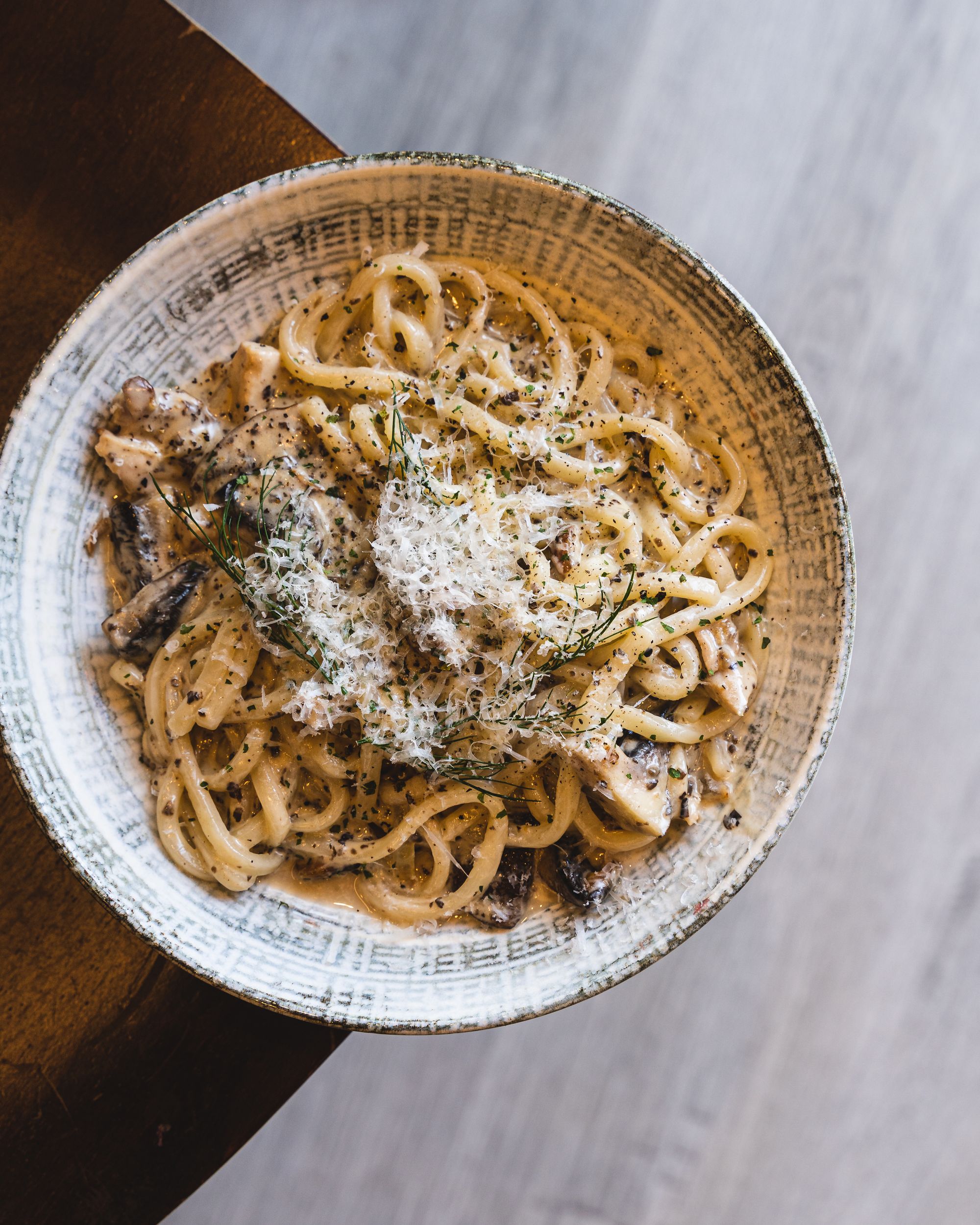 Top down of creamy udon with chicken and shaved cheese on top