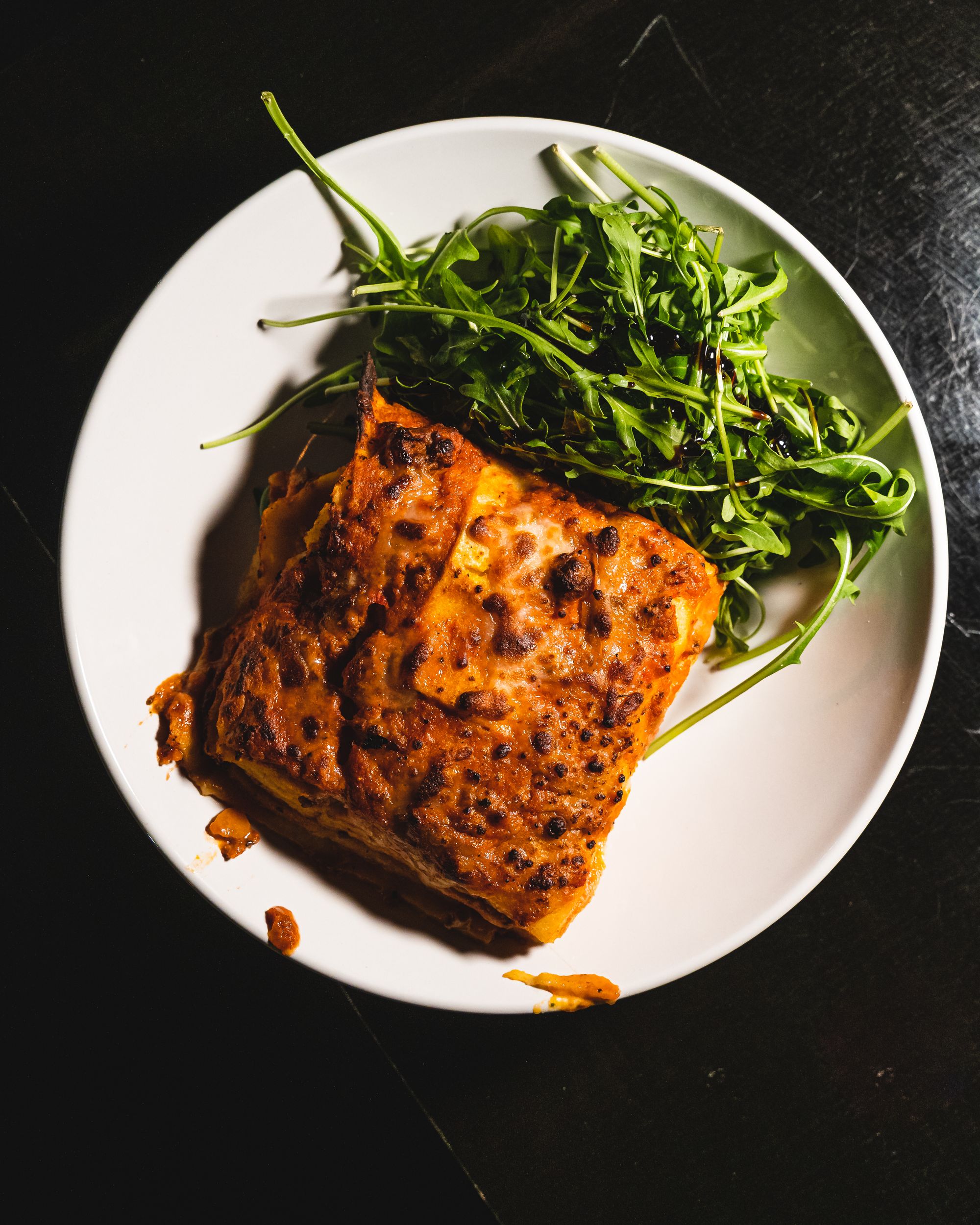 Lasagne on a circular plate served with a side salad