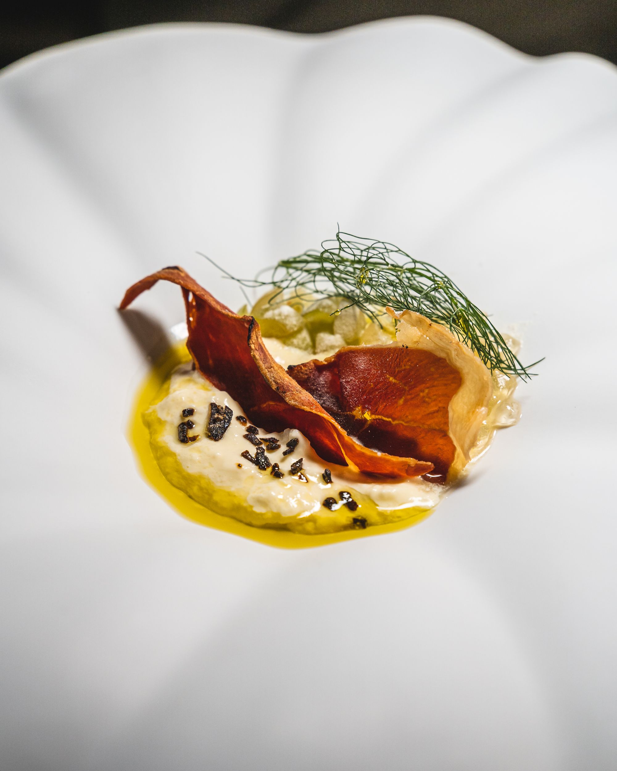 Close up of stracciatella with jamon, grapes and kumato in a flower shaped plate