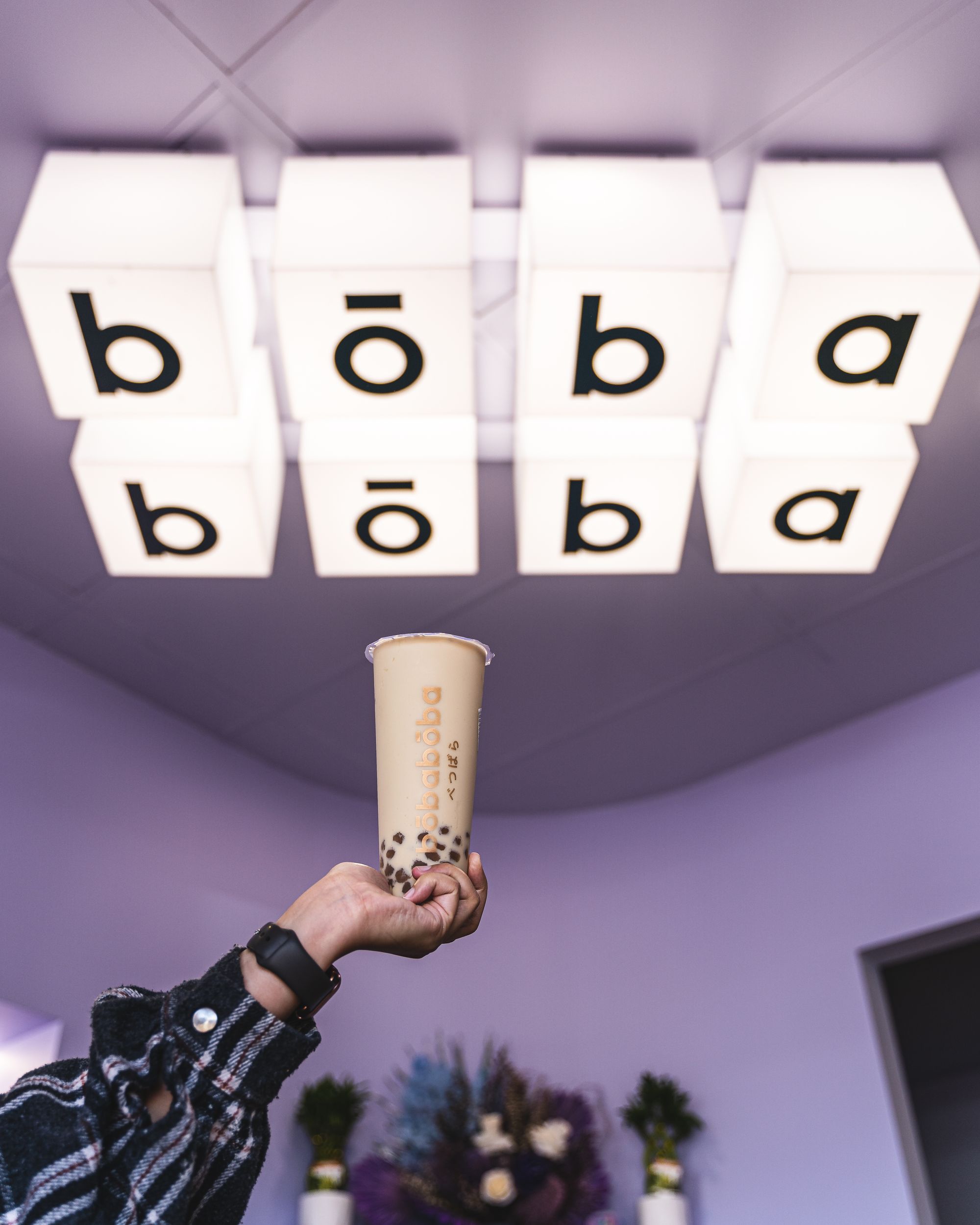 Hand holding boba tea with "boba boba" text in the background