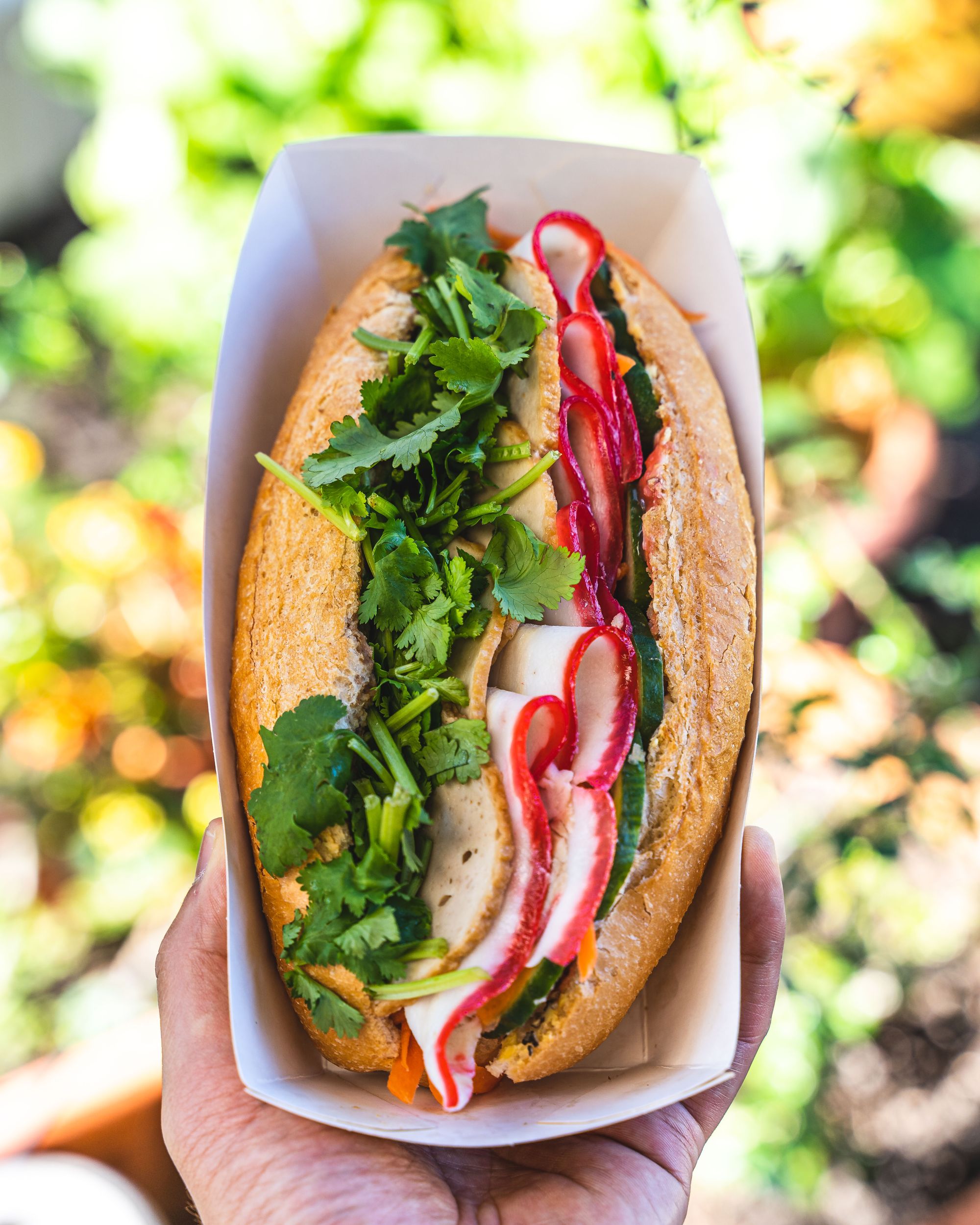 Hand holding banh mi showing all the cold cuts