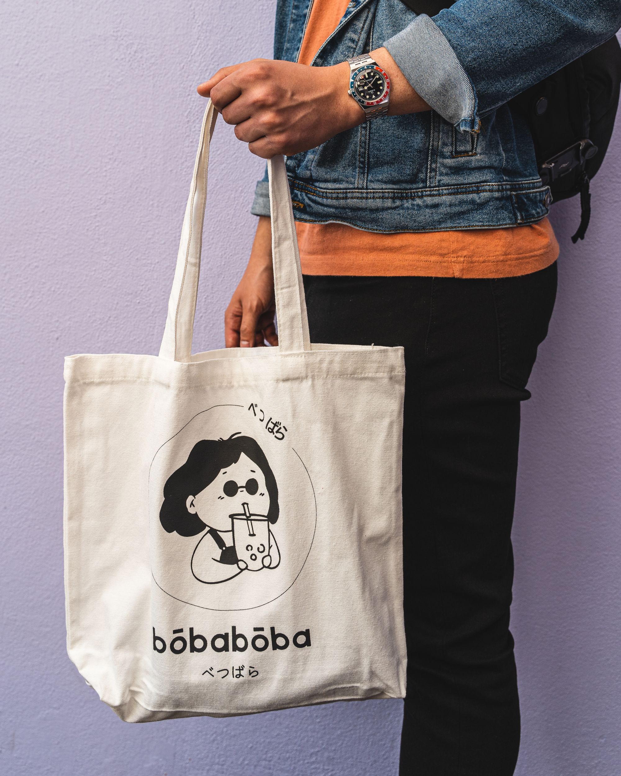 Man holding a white tote bag with a cartoon character sipping buble tea