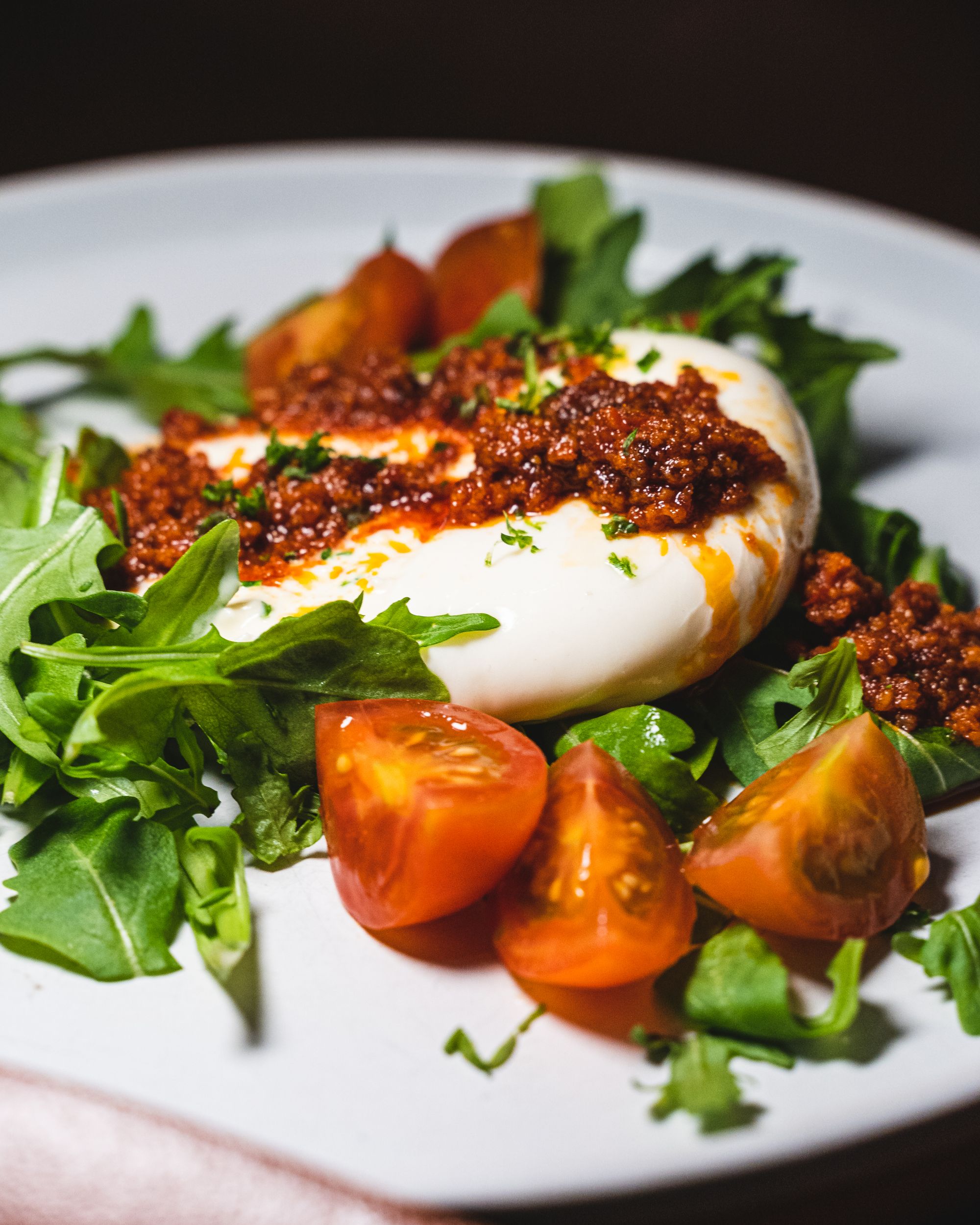 Close up of burrata cheese, assorted green vegetables and cherry tomatoes