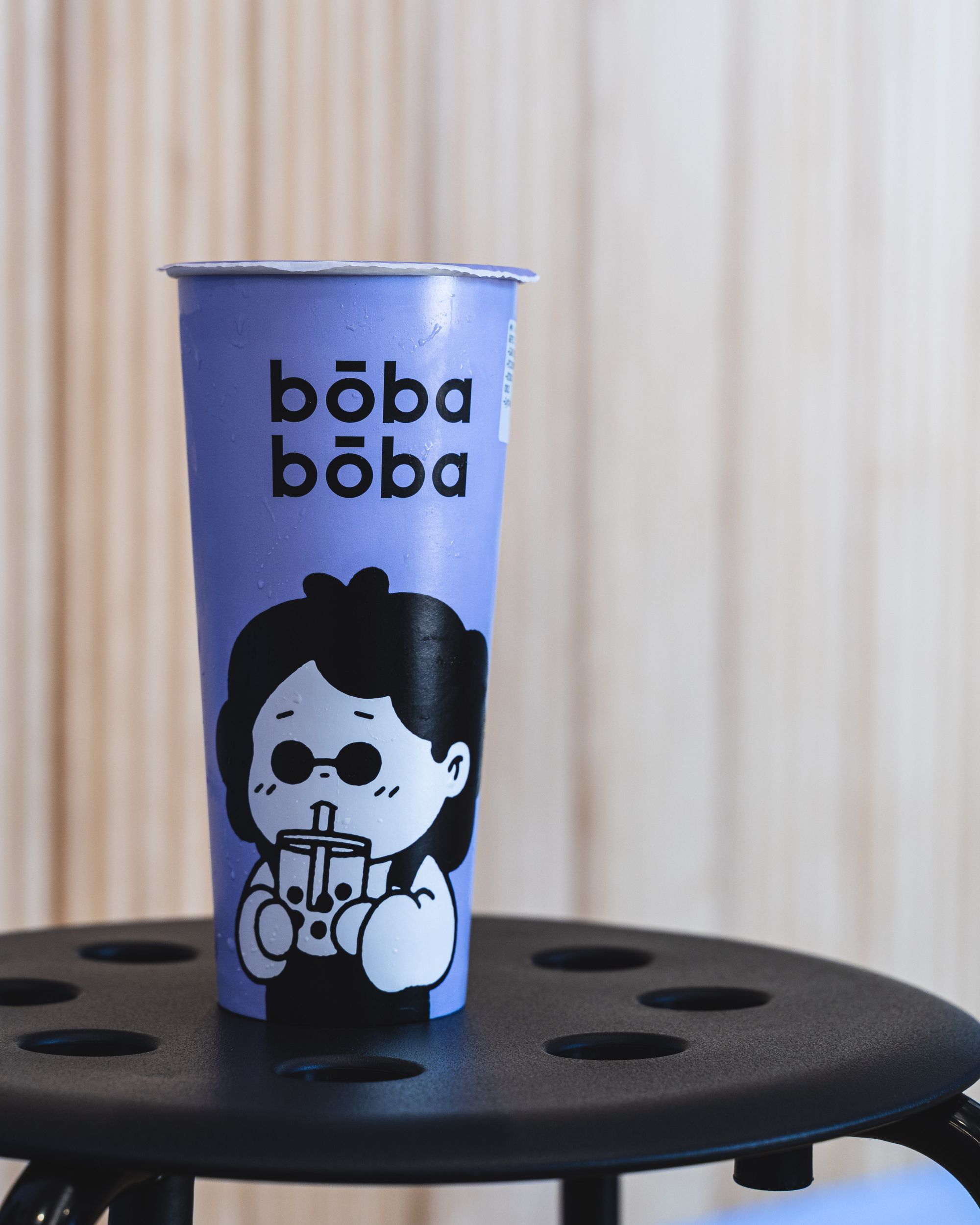 Purple boba cup with "Boba Boba" written on it and a cartoon character drinking boba