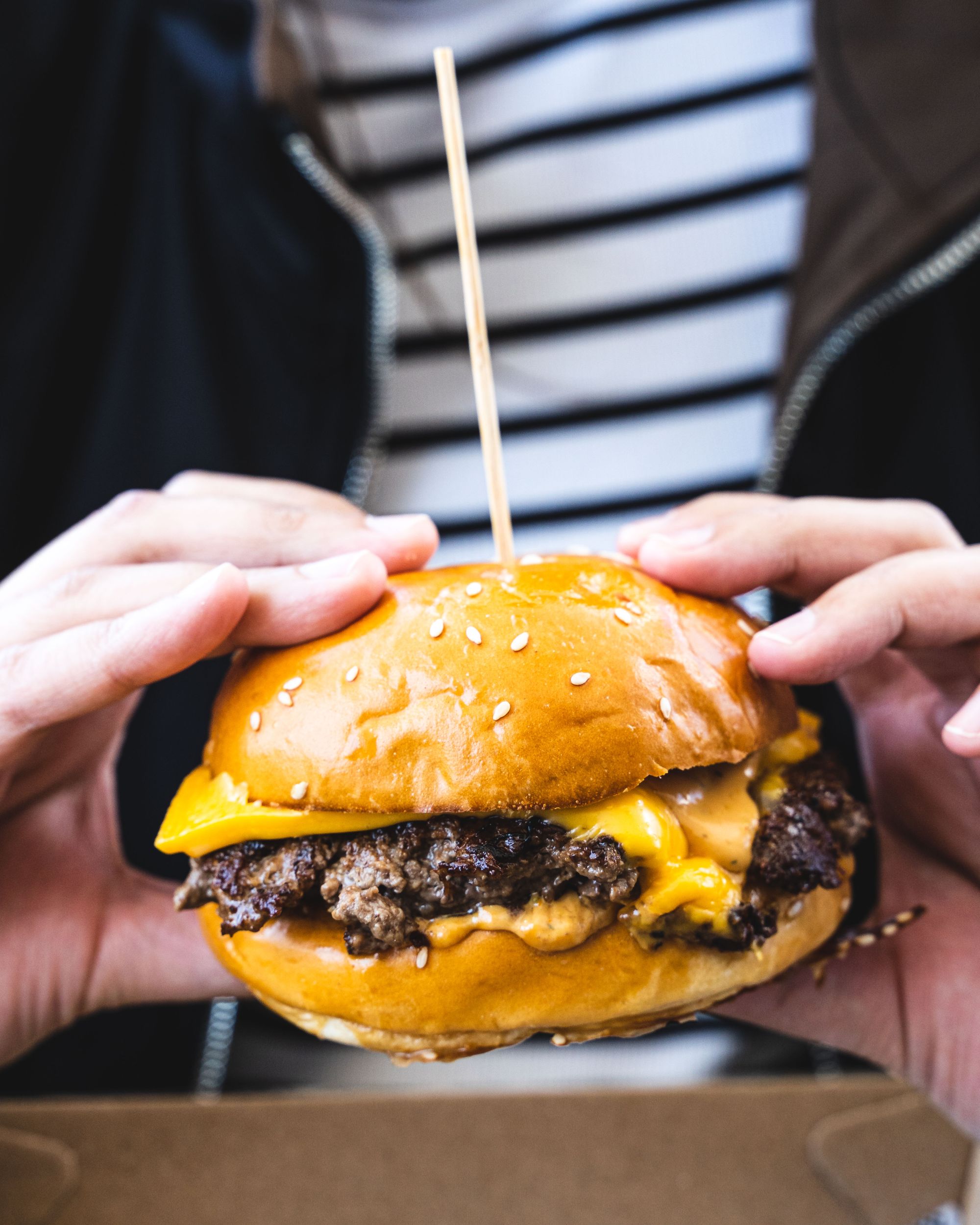 Hand holding a cheeseburger