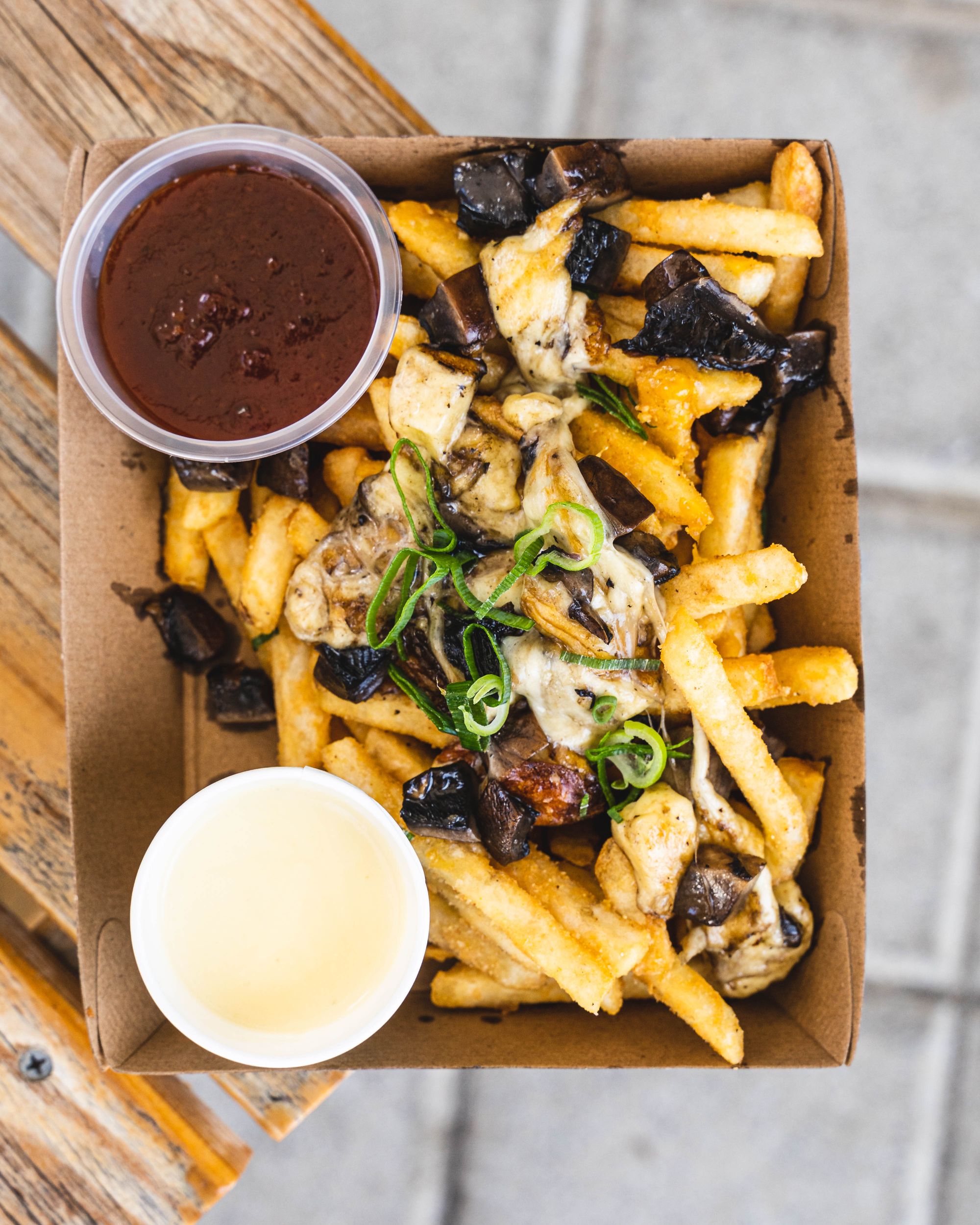 Top down shot of loaded fries with mushrooms, cheese, chilli sauce and garlic cream sauce