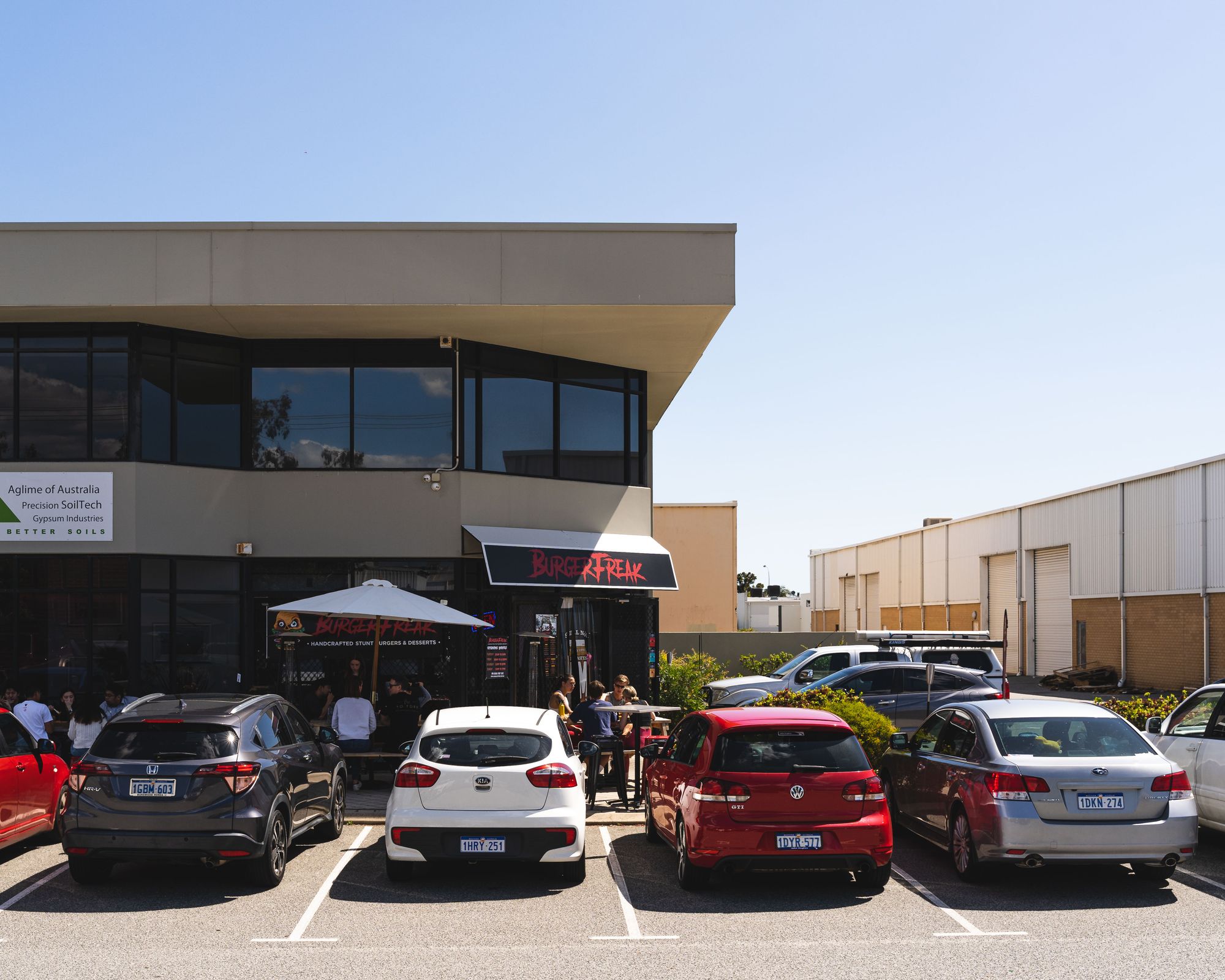 Exterior of BurgerFreak showing cars in the parking lot and people dining outside