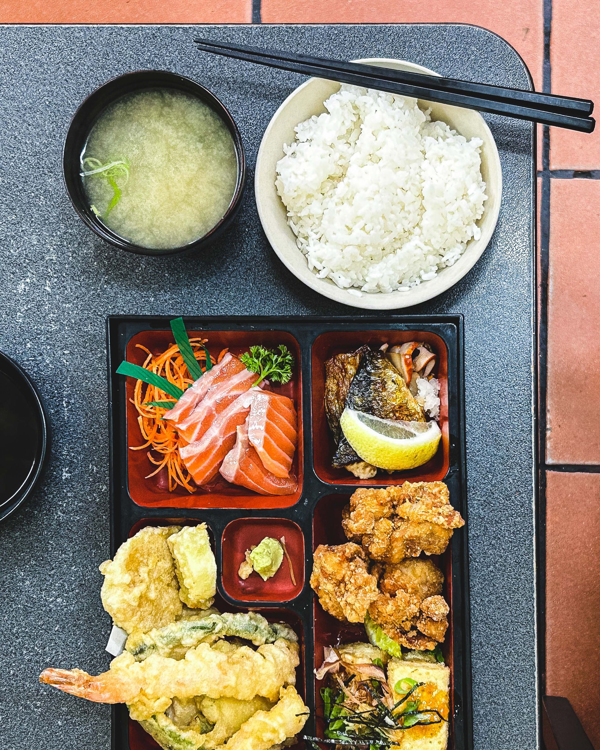 Japanese bento with salmon sashimi, mackerel, karaage, tofu and tempura 