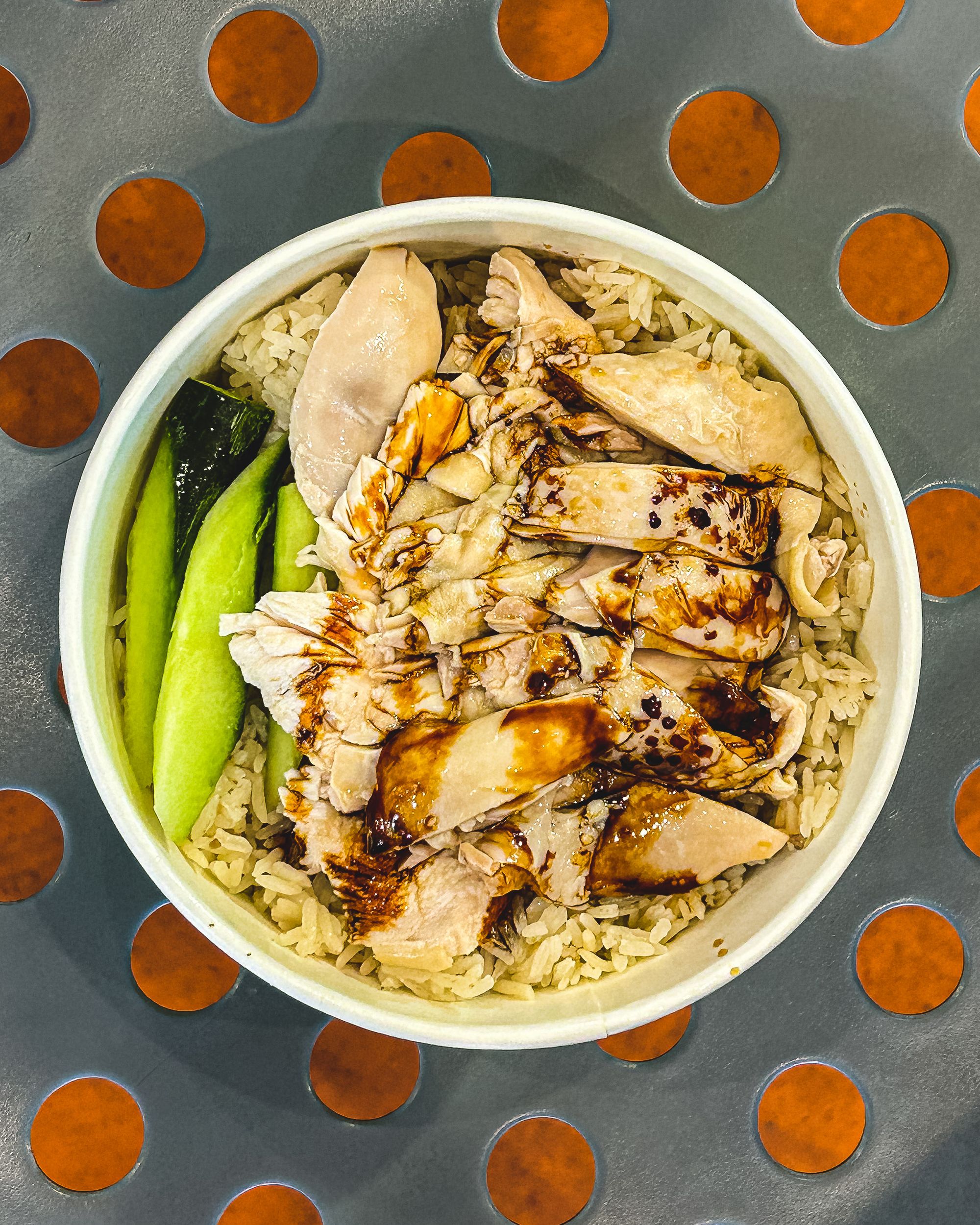 Overhead shot of chicken rice with a drizzle of thick soy sauce and cuts of cucumber