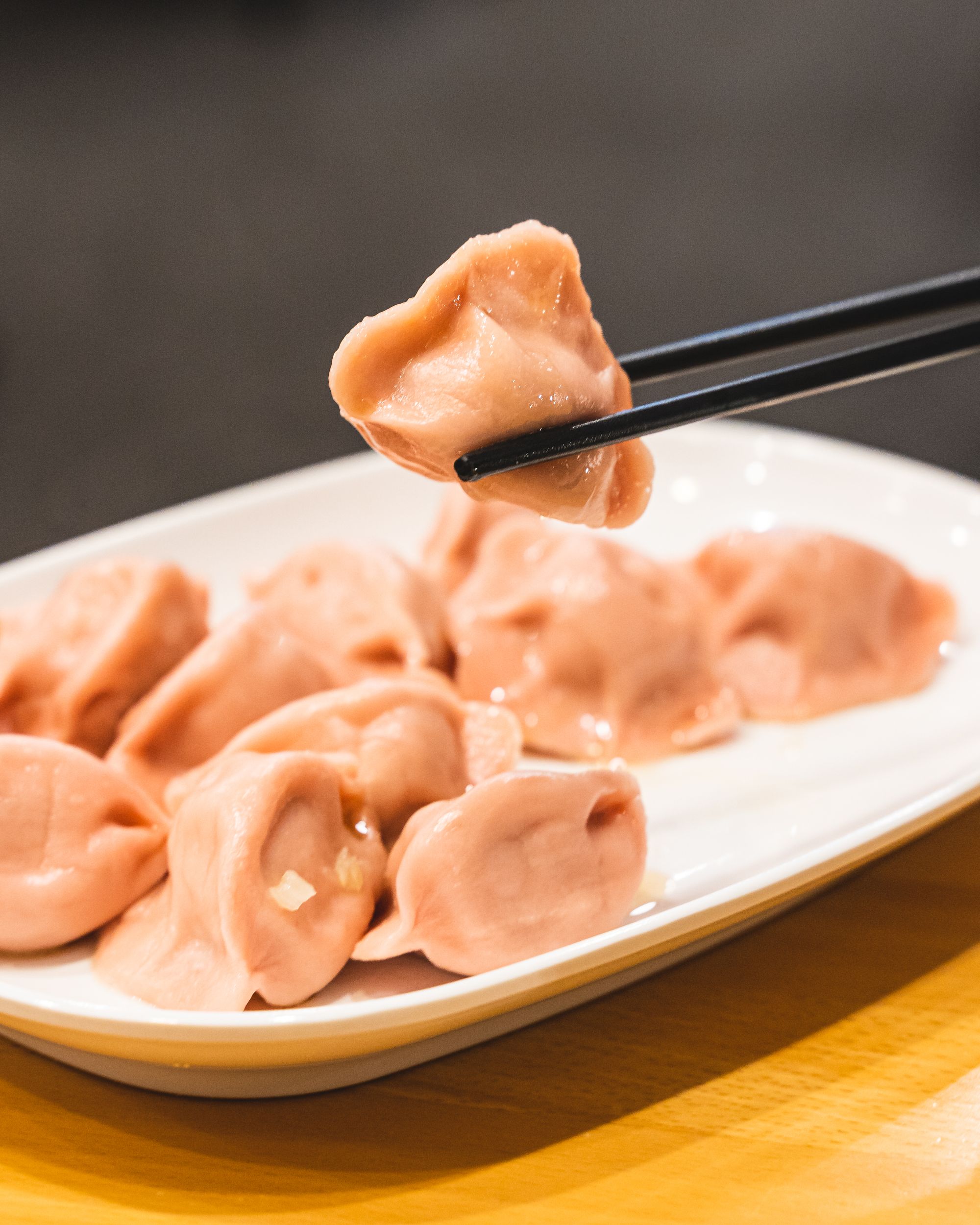 Close up of a chopstick holding up dumplings