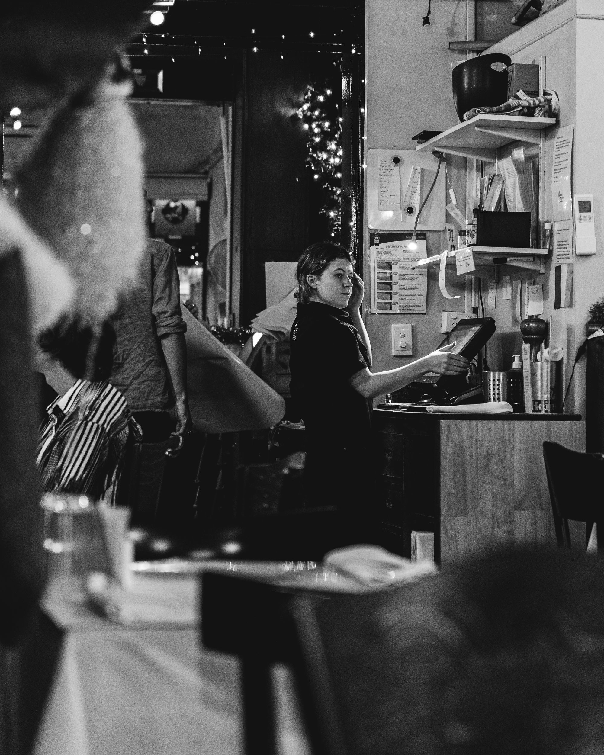 Black and white photo of waitress in restaurant at a ordering terminal