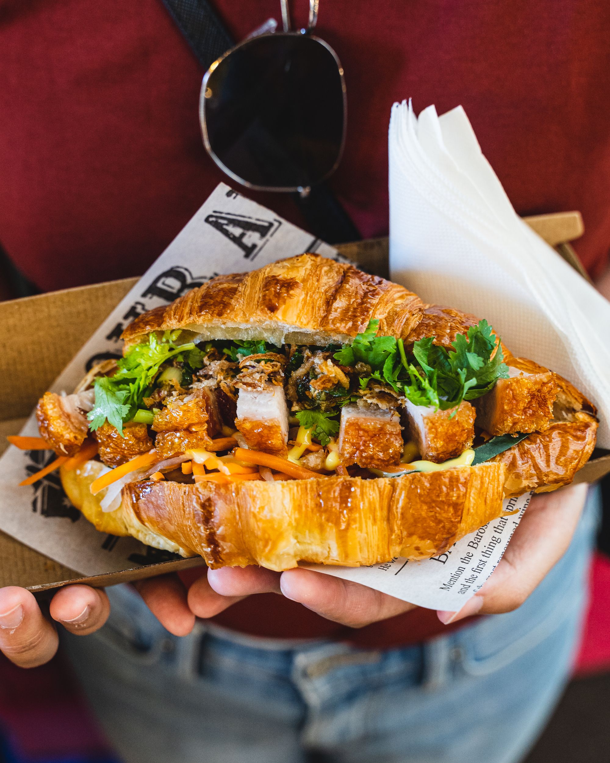 Hand holding a banh mi made with a croissant