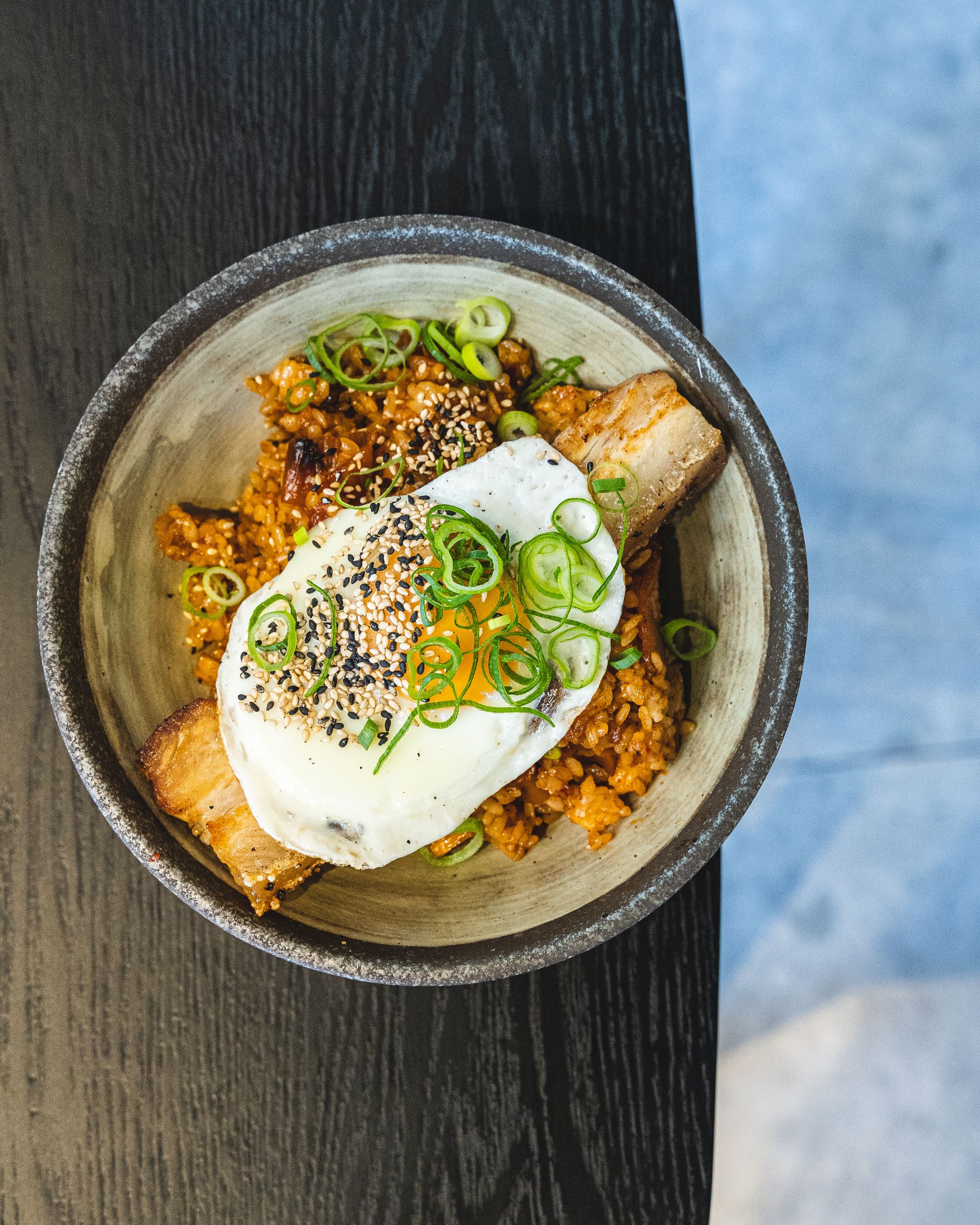 Top down shot of kimchi fried rice with pork belly and a fried egg