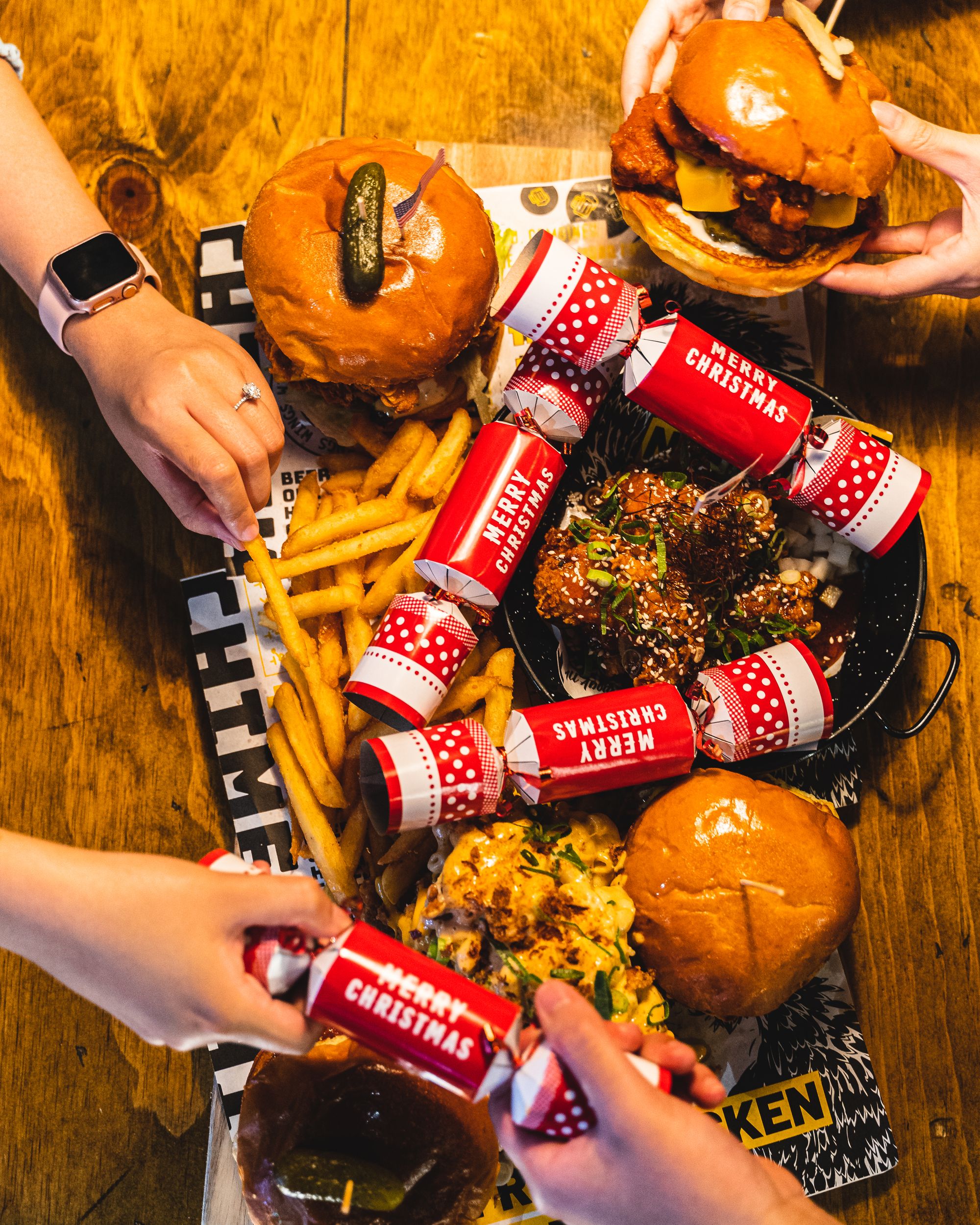 Overhead shot of people reaching into a platter for burgers and chips