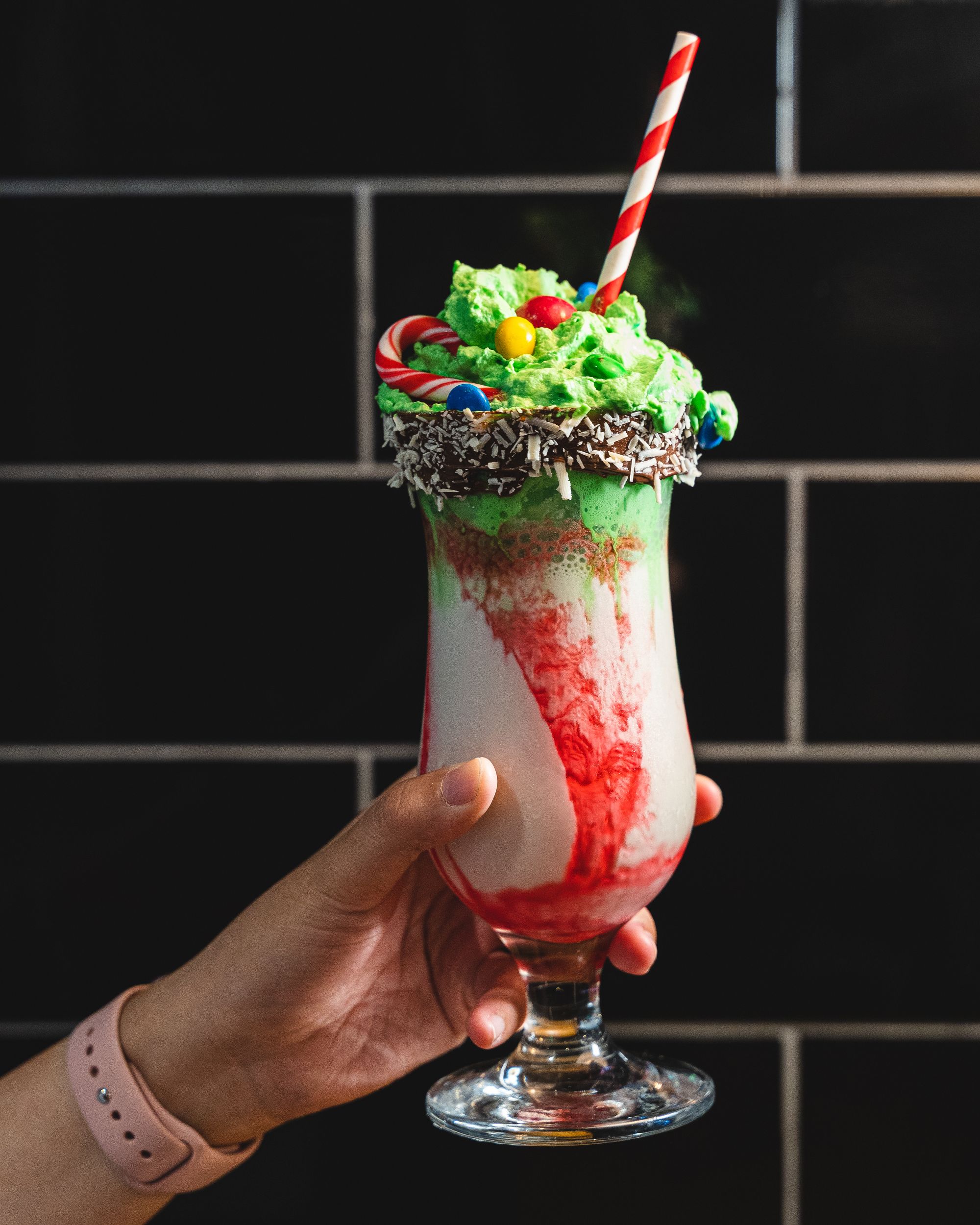 Hand holding a milkshake with green whipped cream