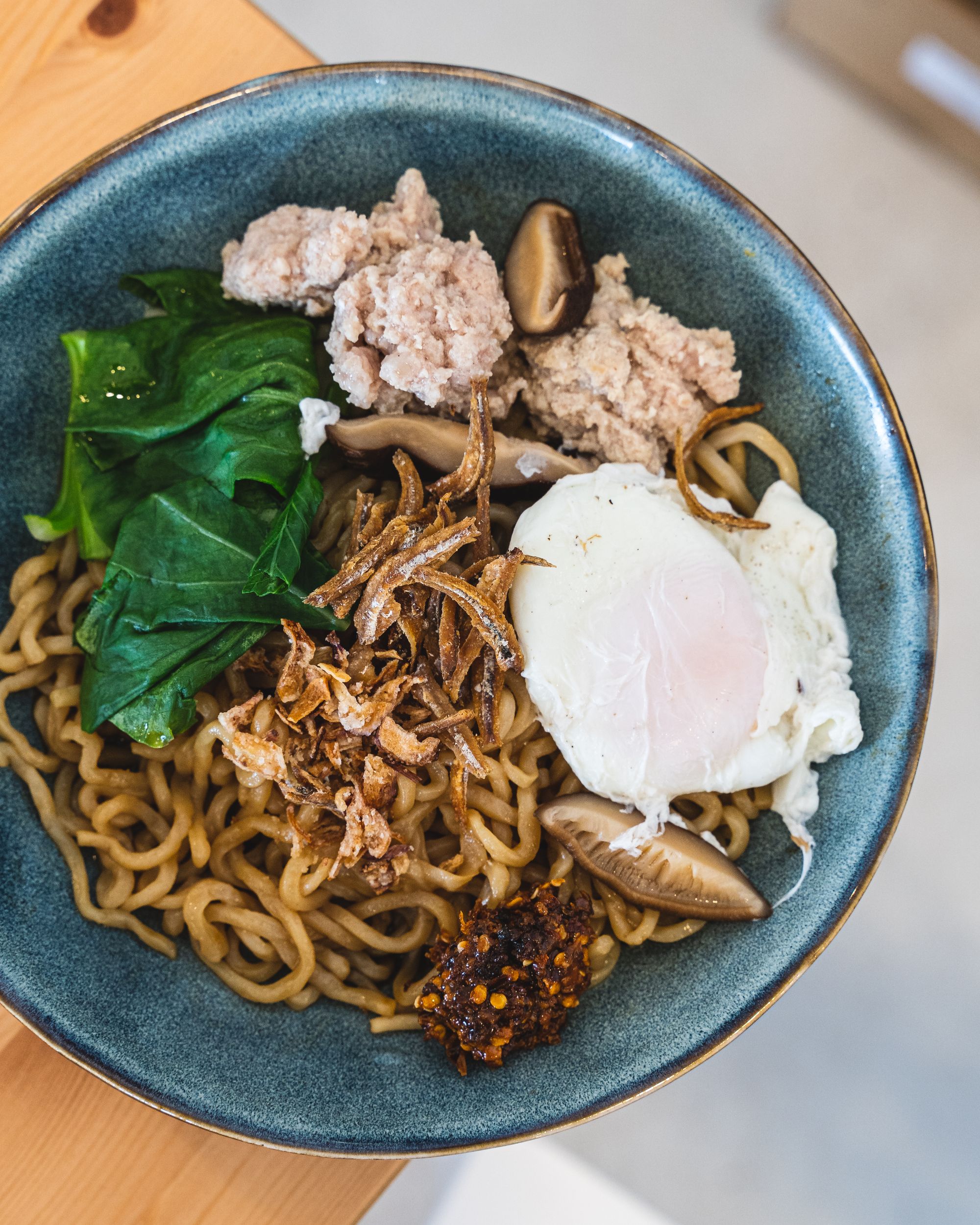 Overhead shot of noodles with greens, pork mince, egg and shiitake mushrooms