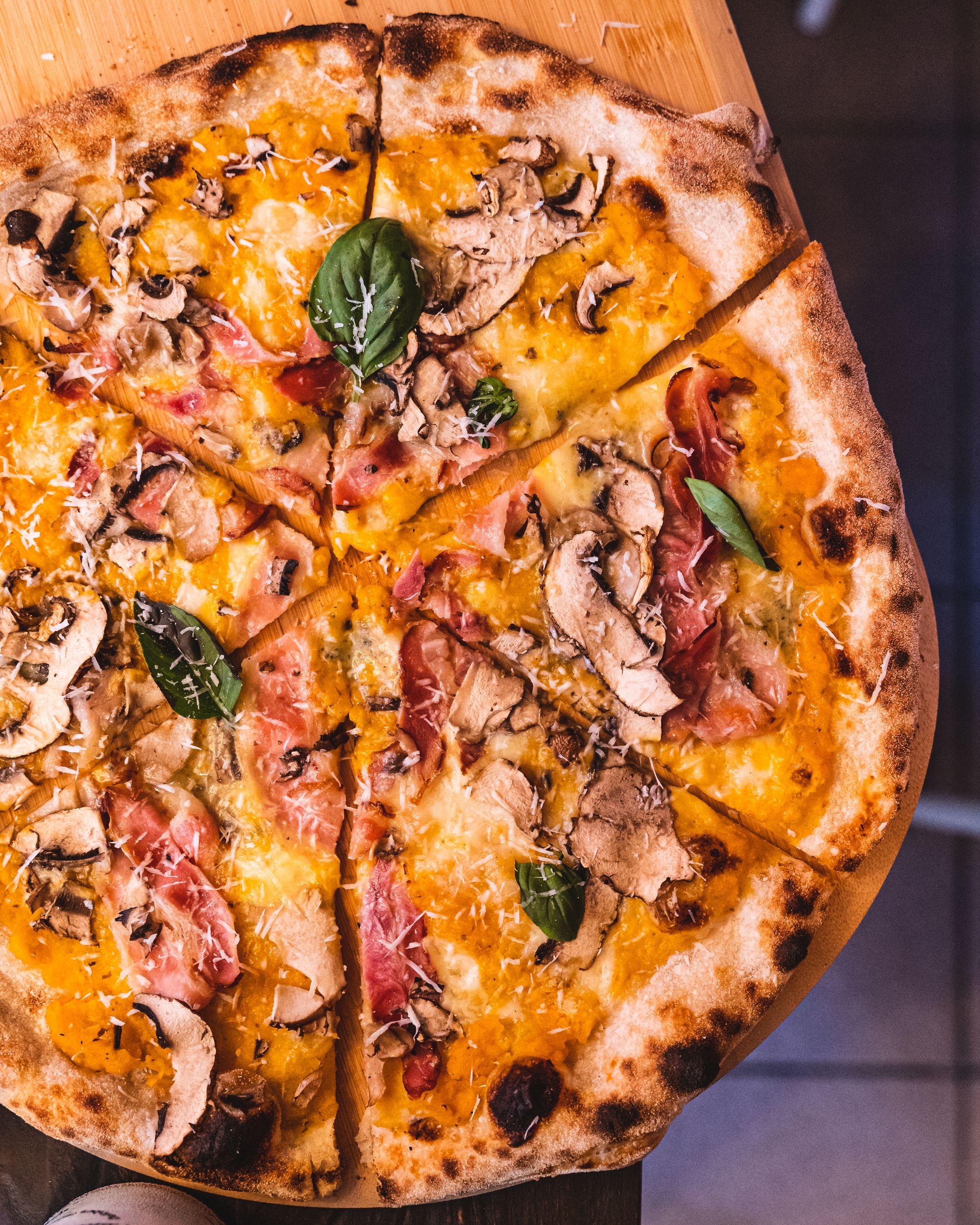 Top down shot of pizza with mushrooms, basil and ham