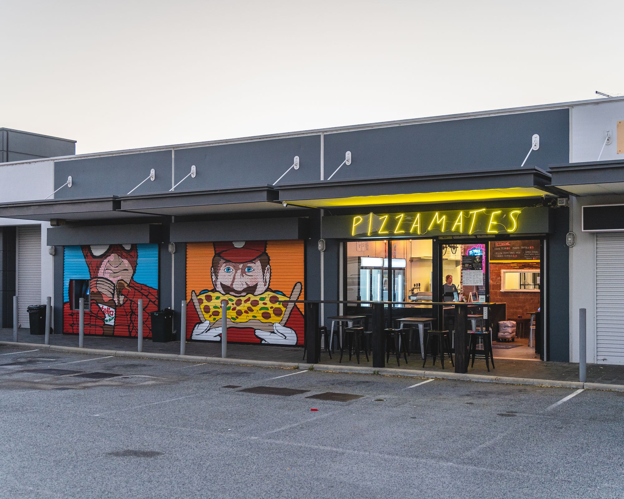 Exterior shot of PIZZA MATES showing Spiderman and Mario cartoon paintings eating pizza