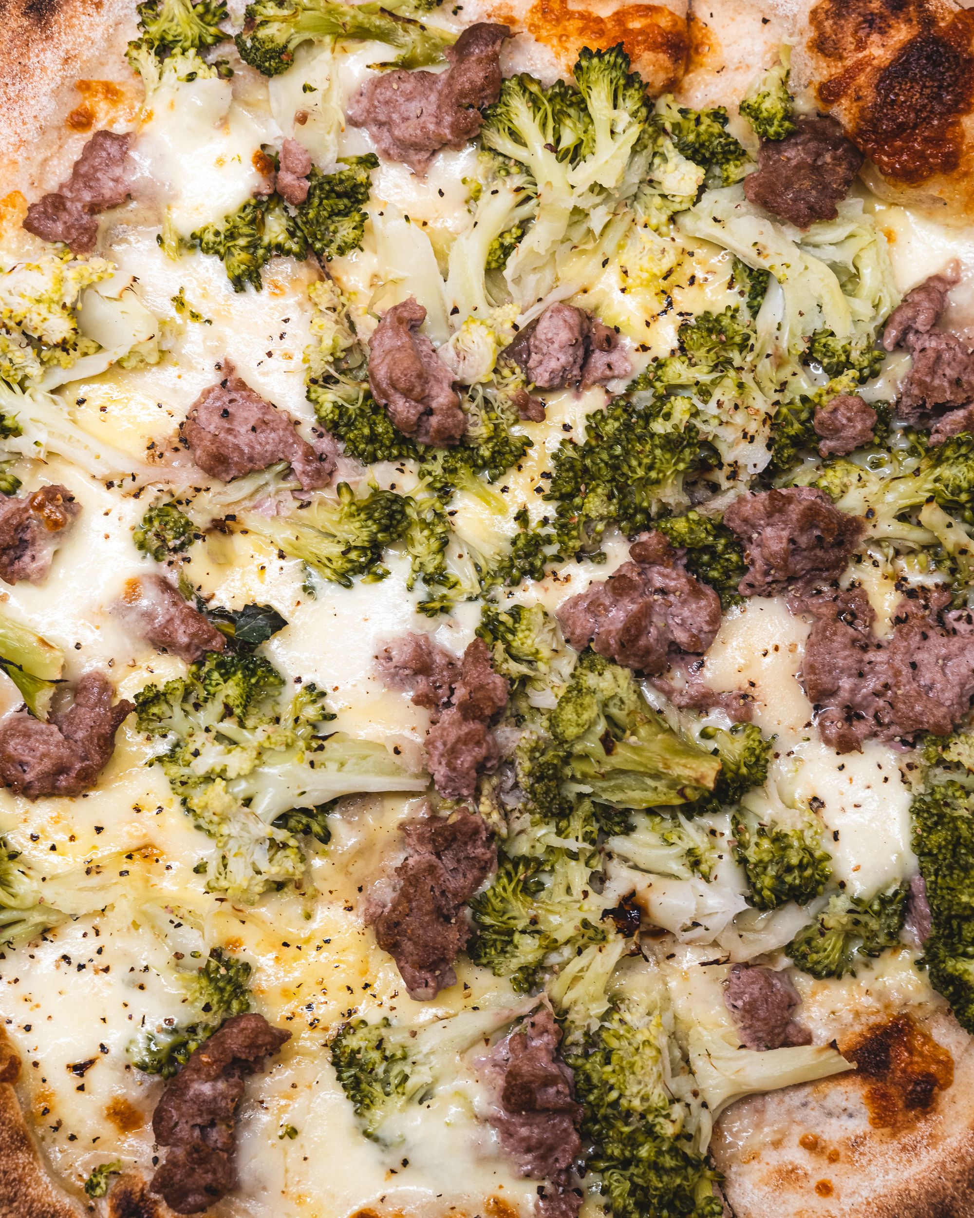 Close up of pizza with lamb, broccoli and cheese