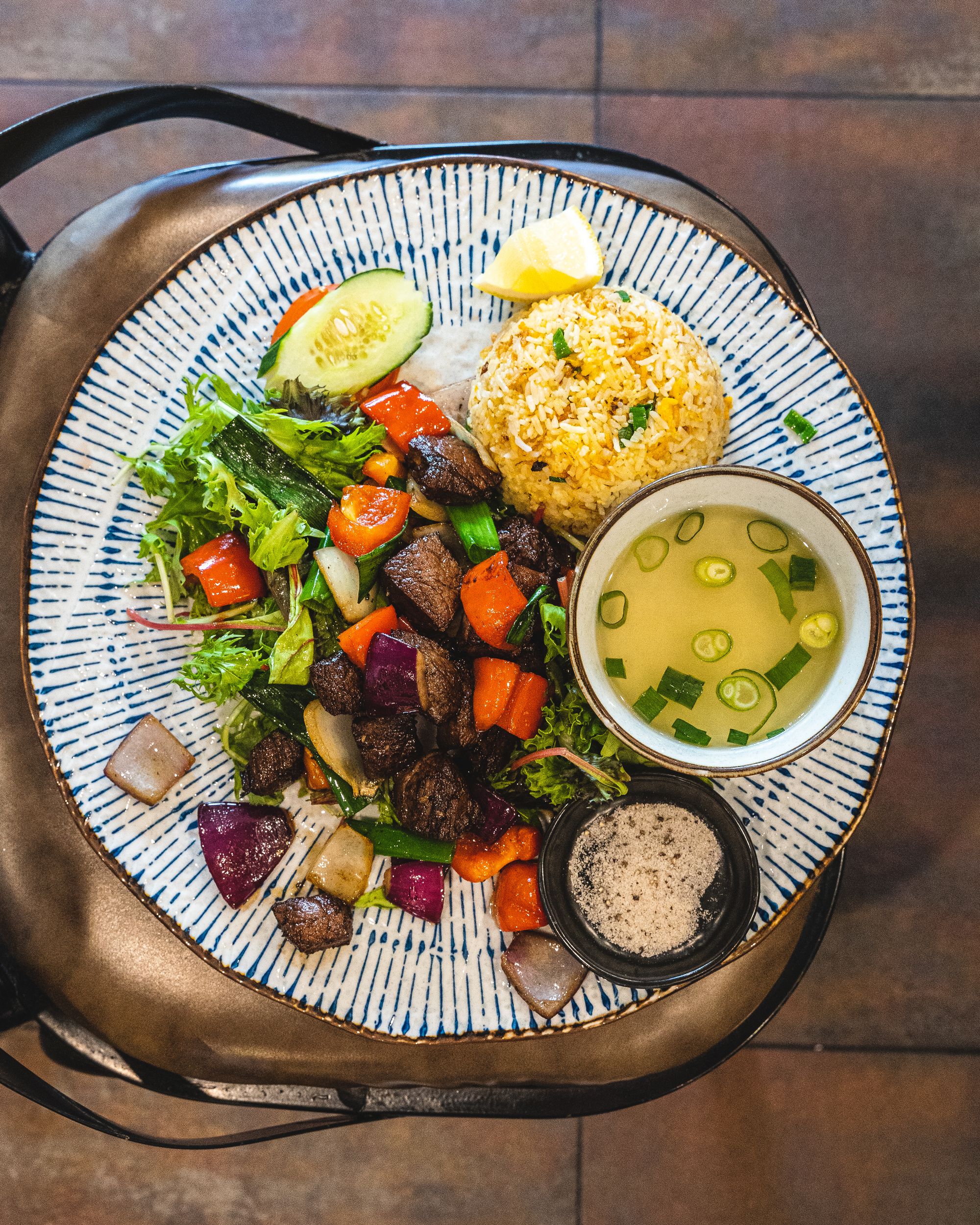 Top down shot of Vietnamese shaking beef with soup and rock salt on the side