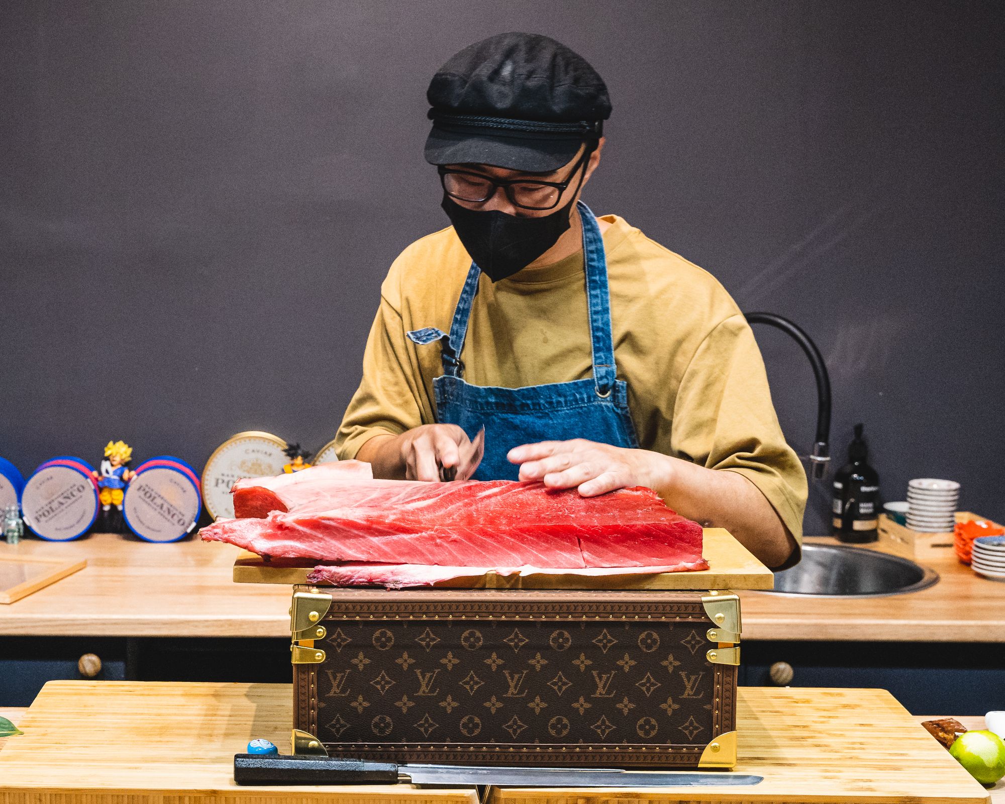 Chef slicing tuna on top of a LV branded chest