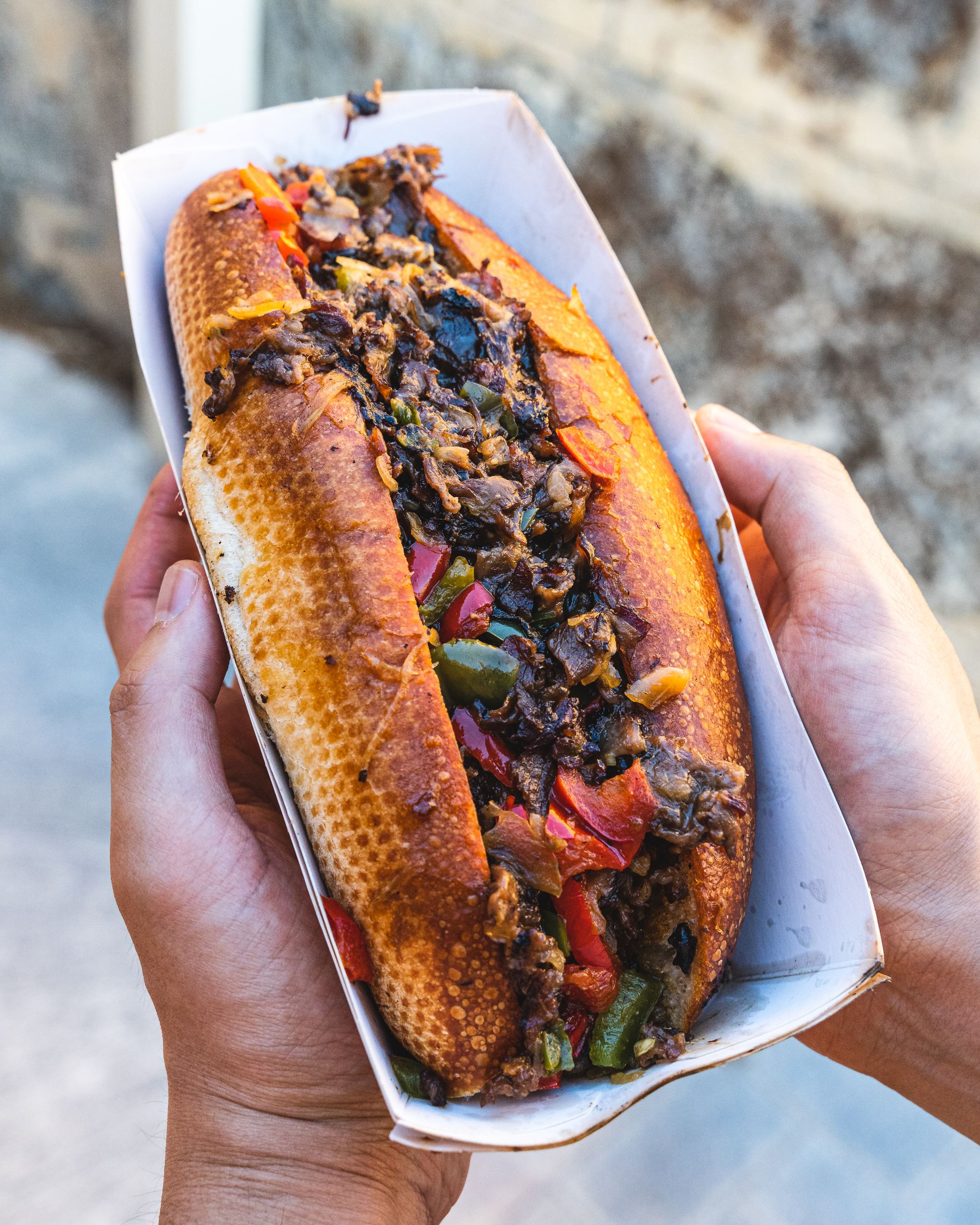 Hand holding a philly cheese steak