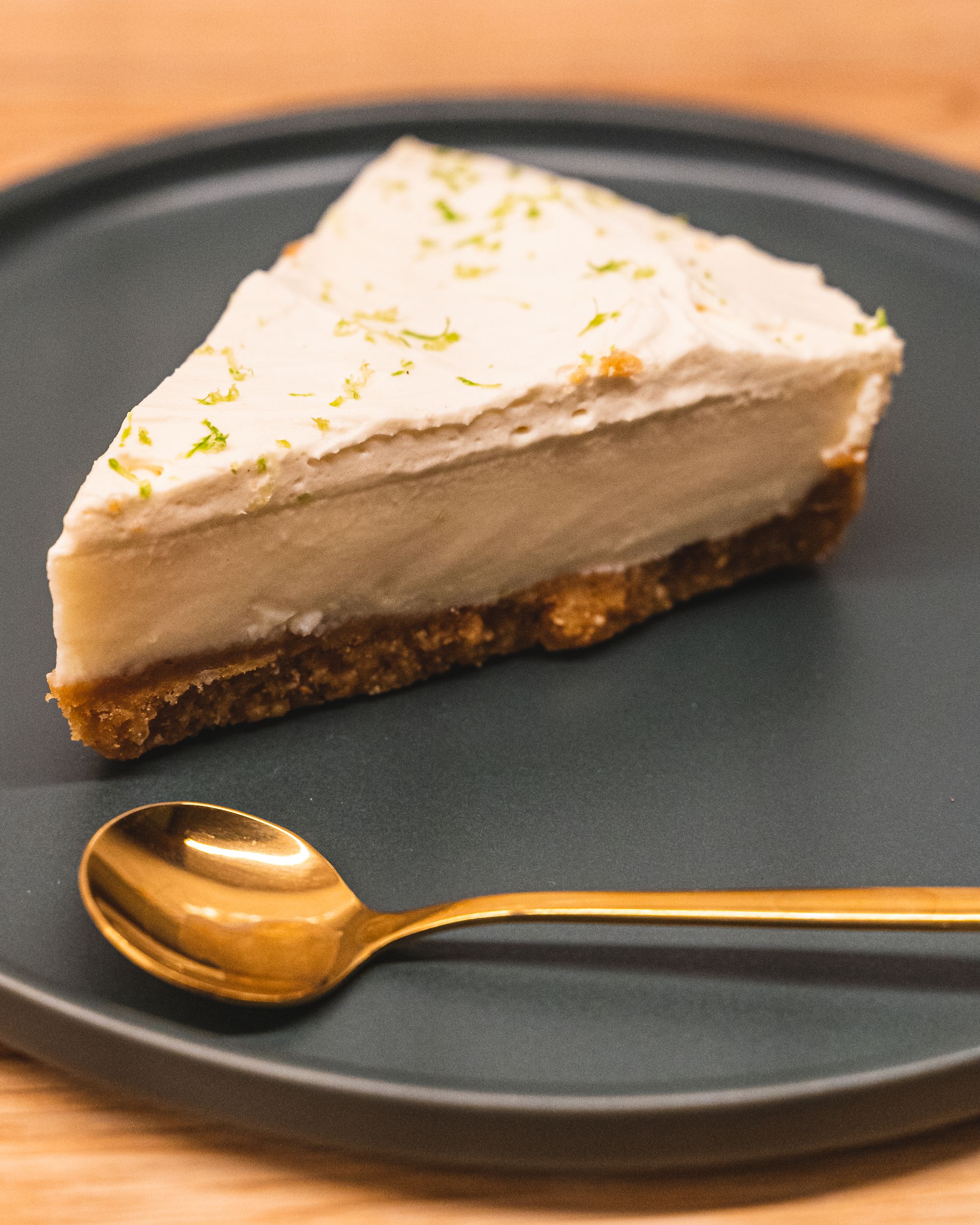 Slice of key lime pie with gold spoon, sitting on a green plate