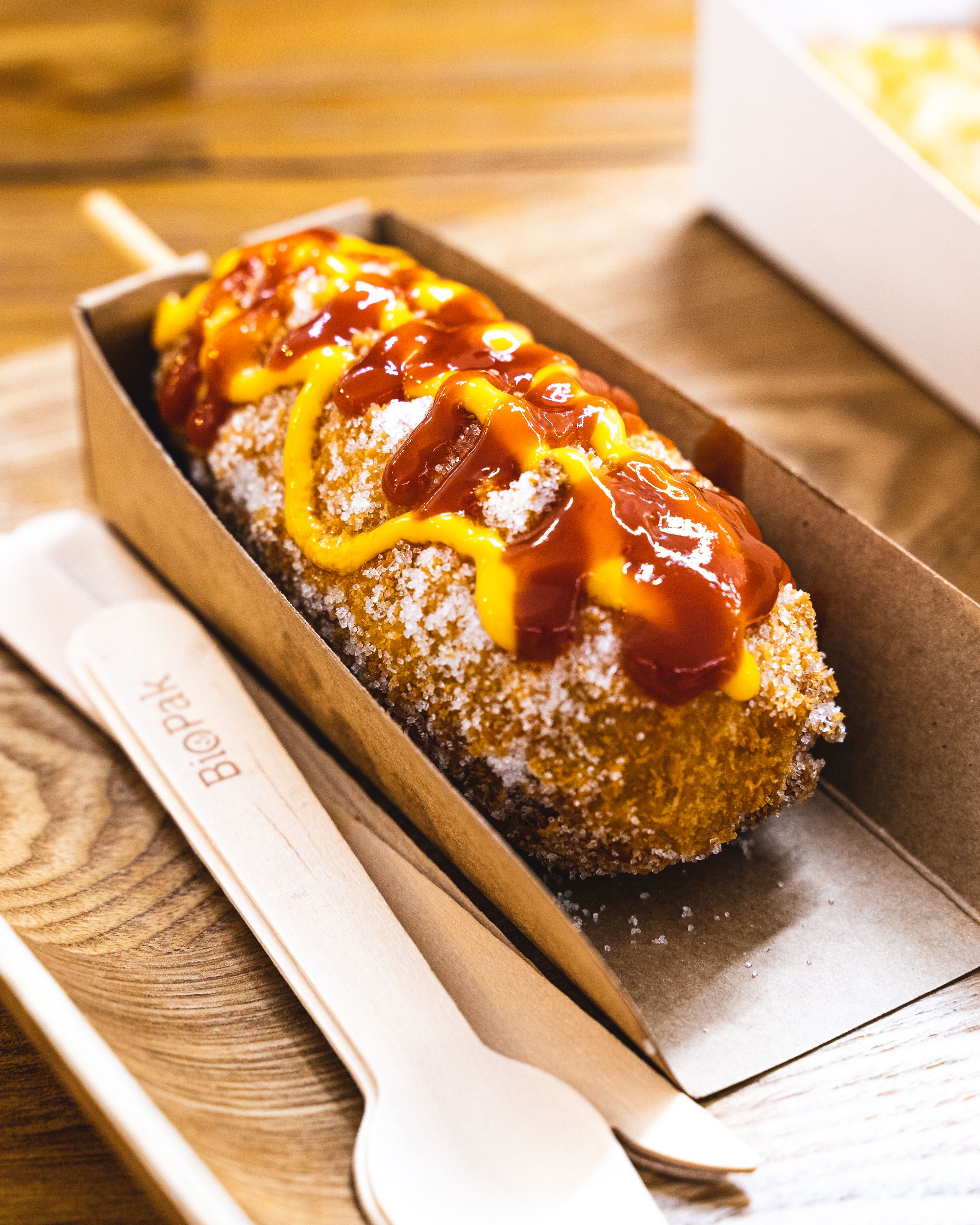Close up of Korean corn dog with mustard and tomato sauce