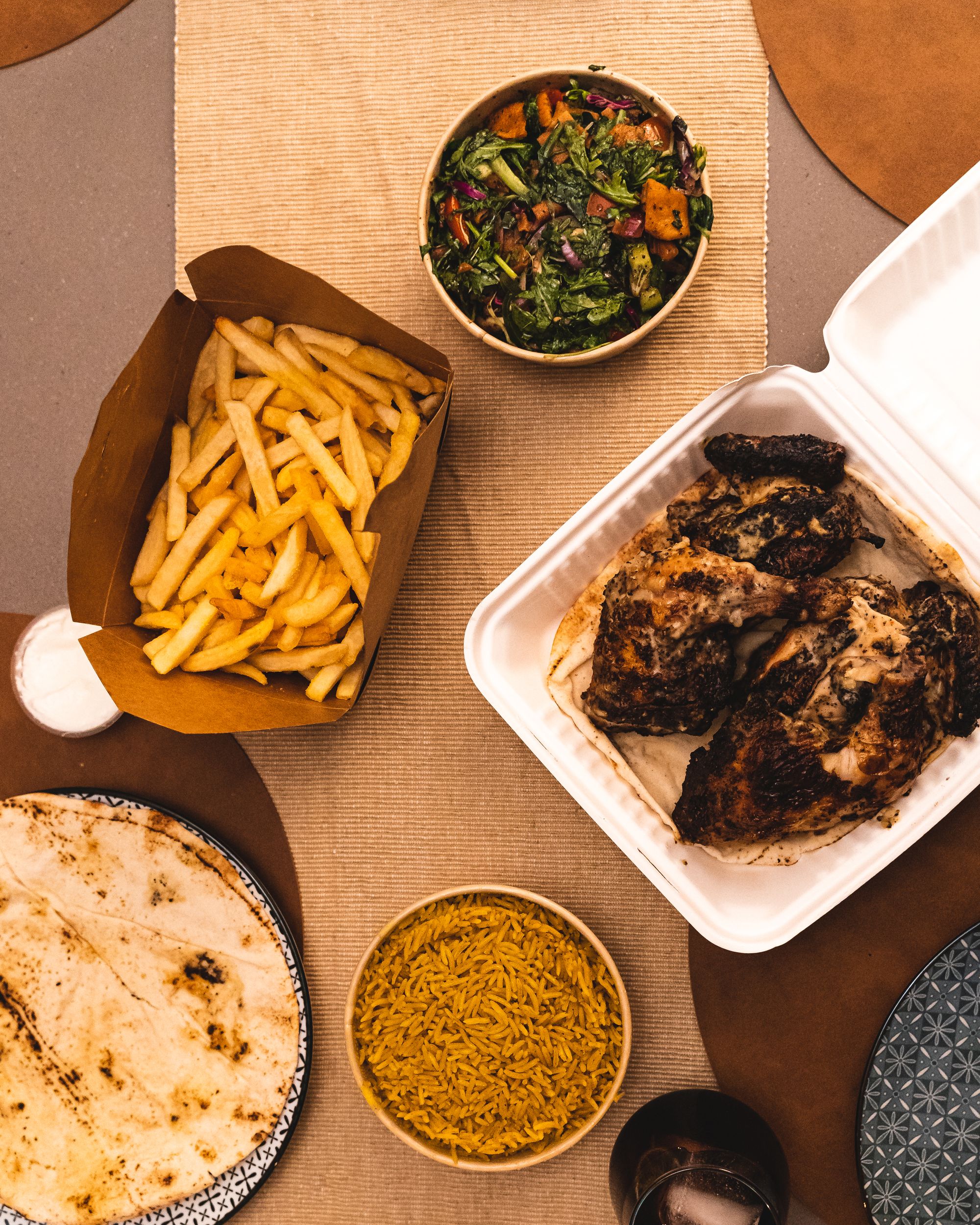 Top down shot of chips, fatoush salad, chicken, rice and Lebanese bread