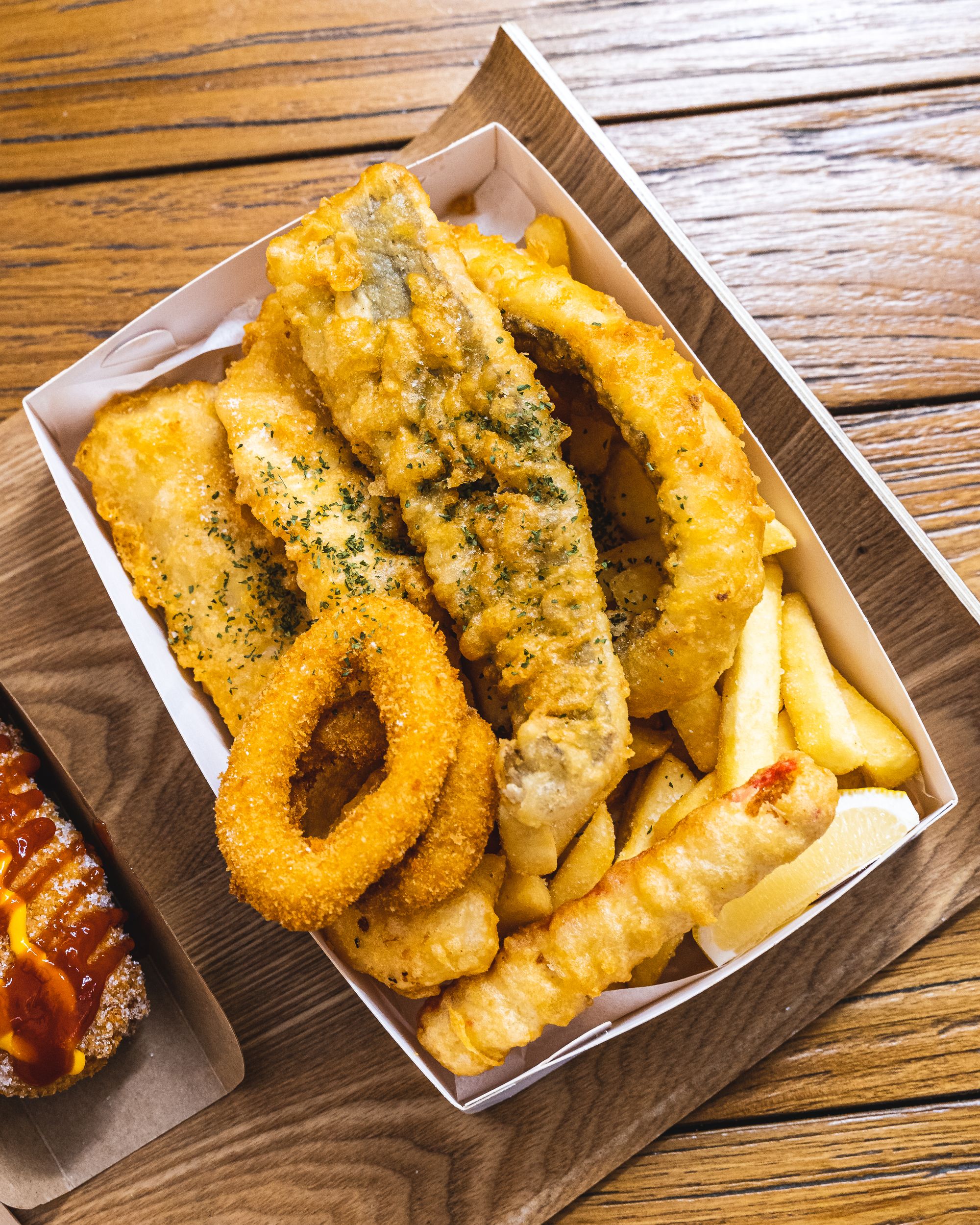 Top down of fish and chips with a squid ring, crab stick and lemon