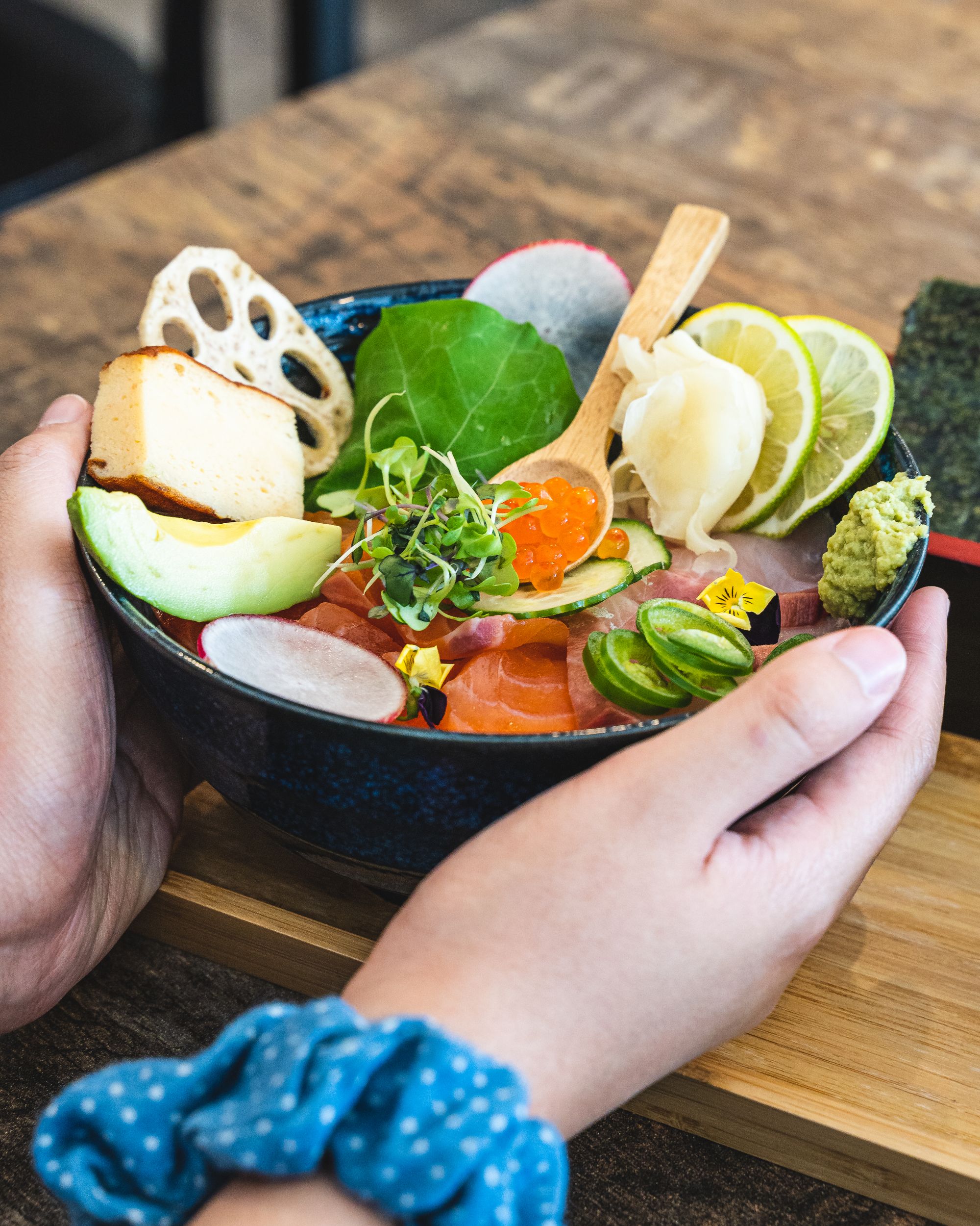 Hand holding a bowl with various sashimi cuts