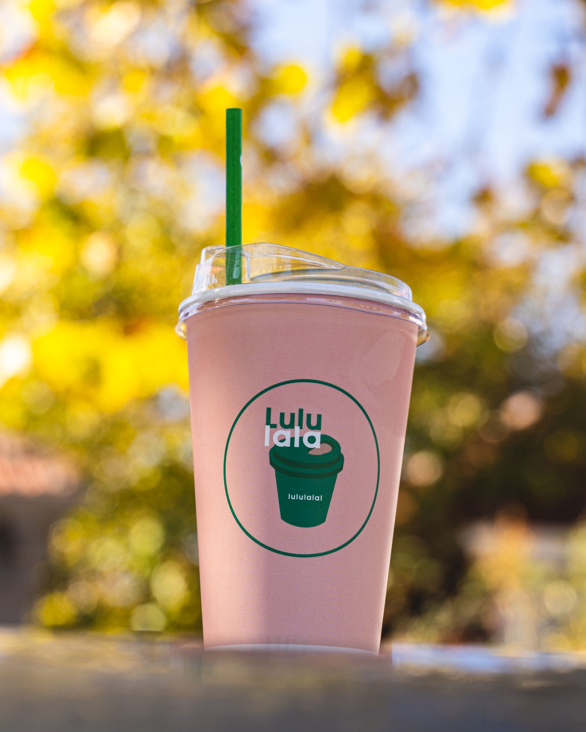 Close up of pink coffee cup with a green straw