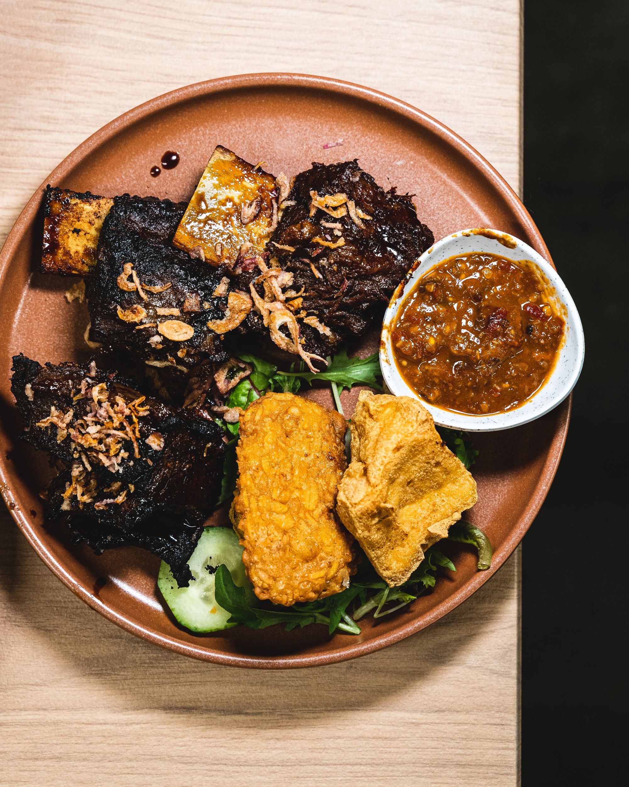 Top down shot of beef ribs with sambal and tempeh