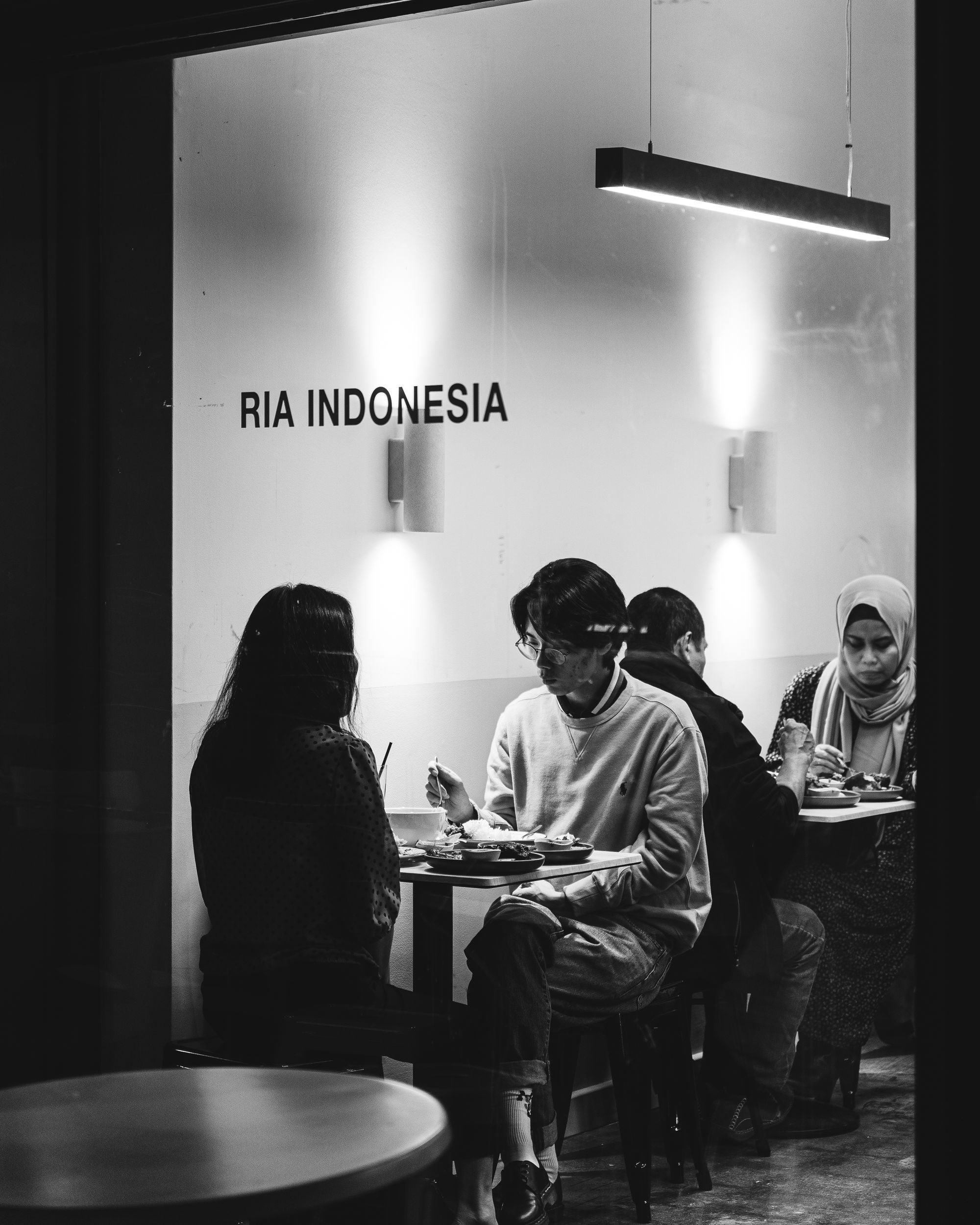 Black and white photo of customers eating inside of Ria Ayam Penyet