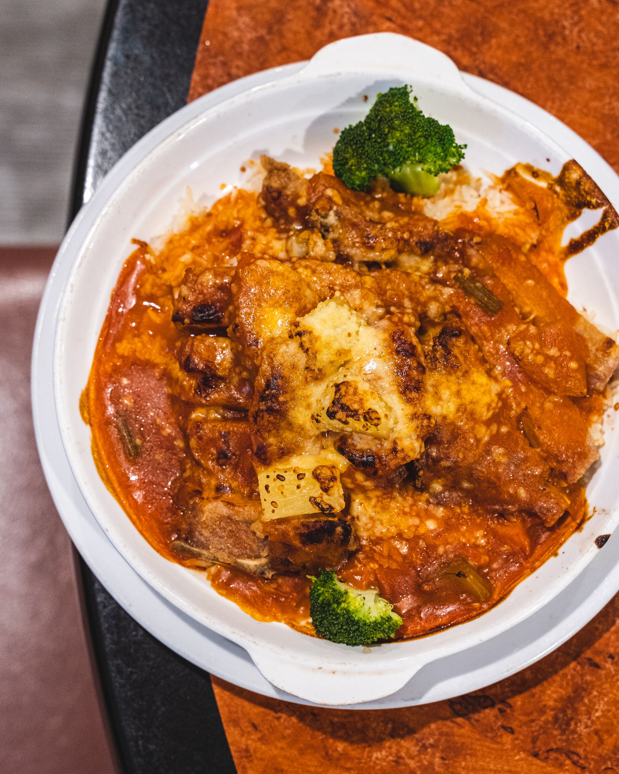 Top down shot of fried pork chop with a tomato sauce with broccoli as garnish