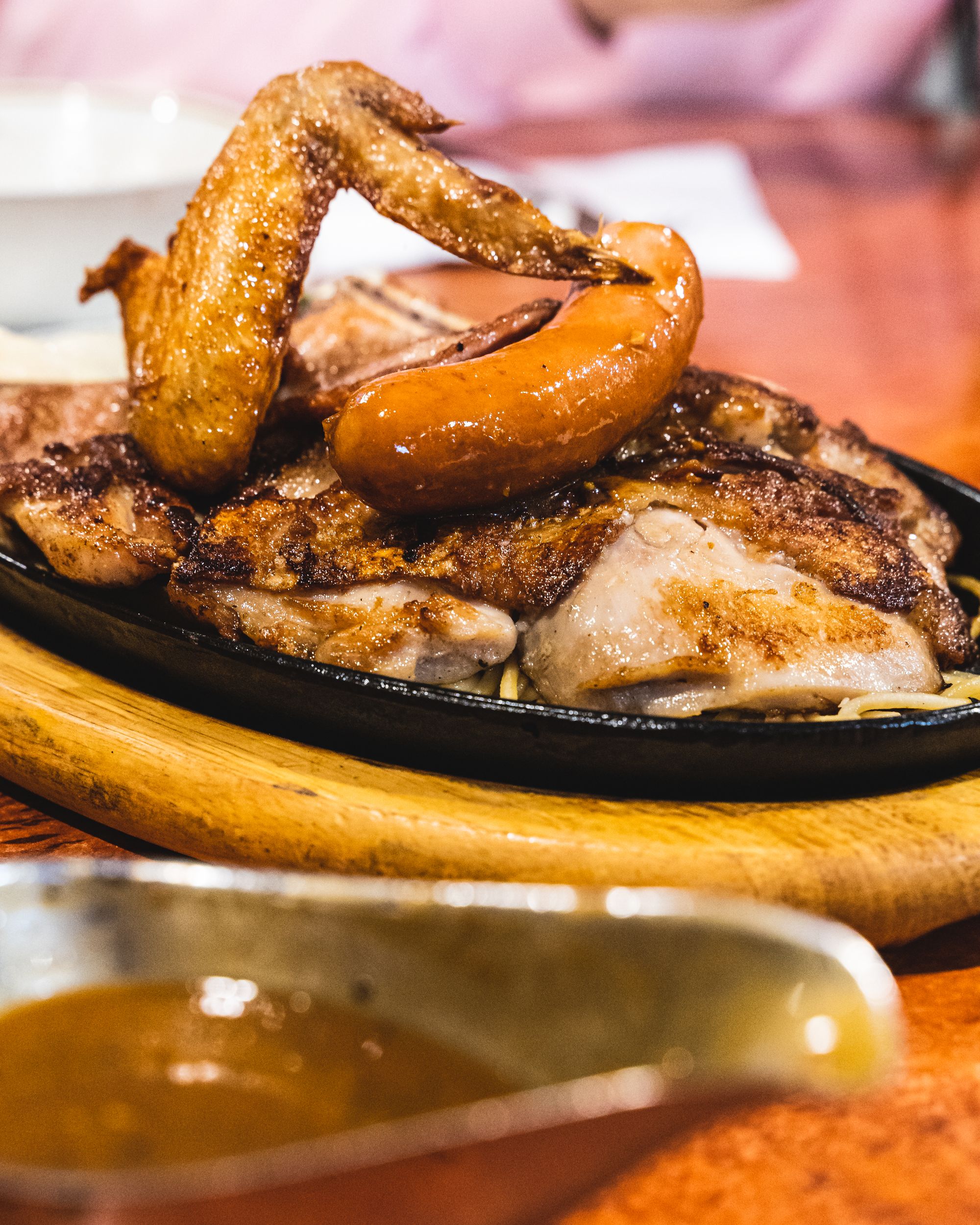 Close up of sizzling hot plate with a chicken wing, pork chop, chicken chop and sausage