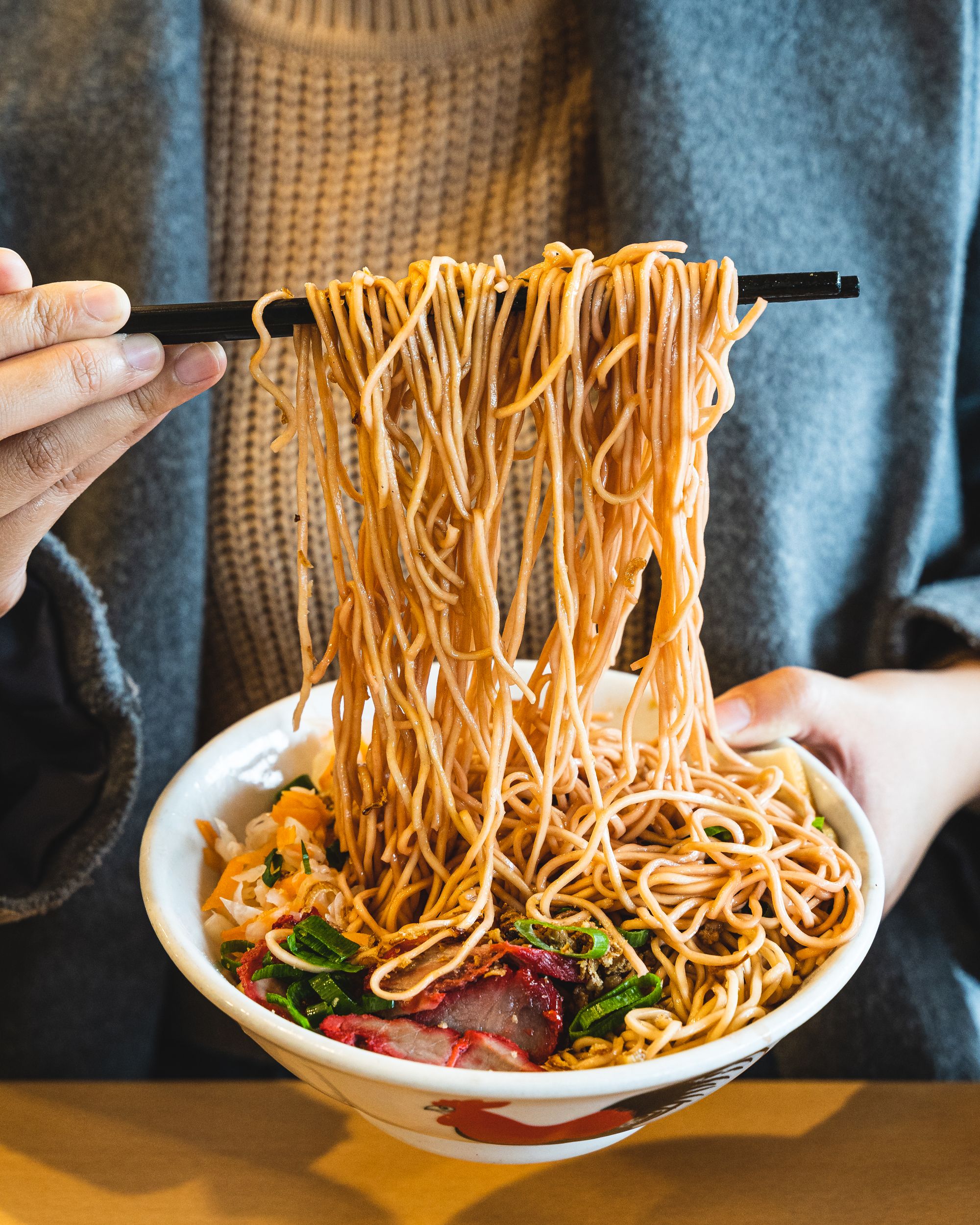 Chopsticks picking up  noodles from a bowl