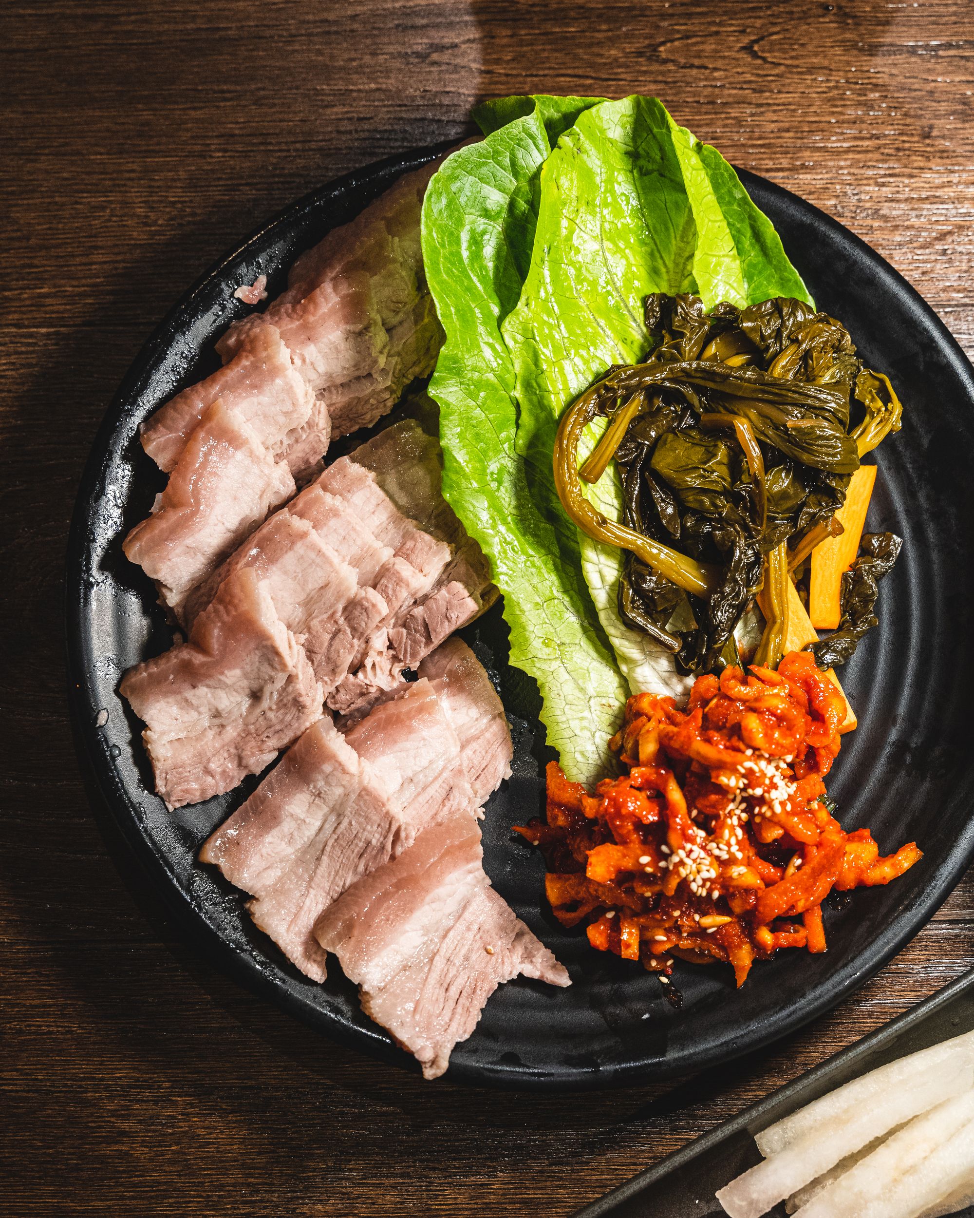 Top down of Korean bossam, pork belly, lettuce and kimchi