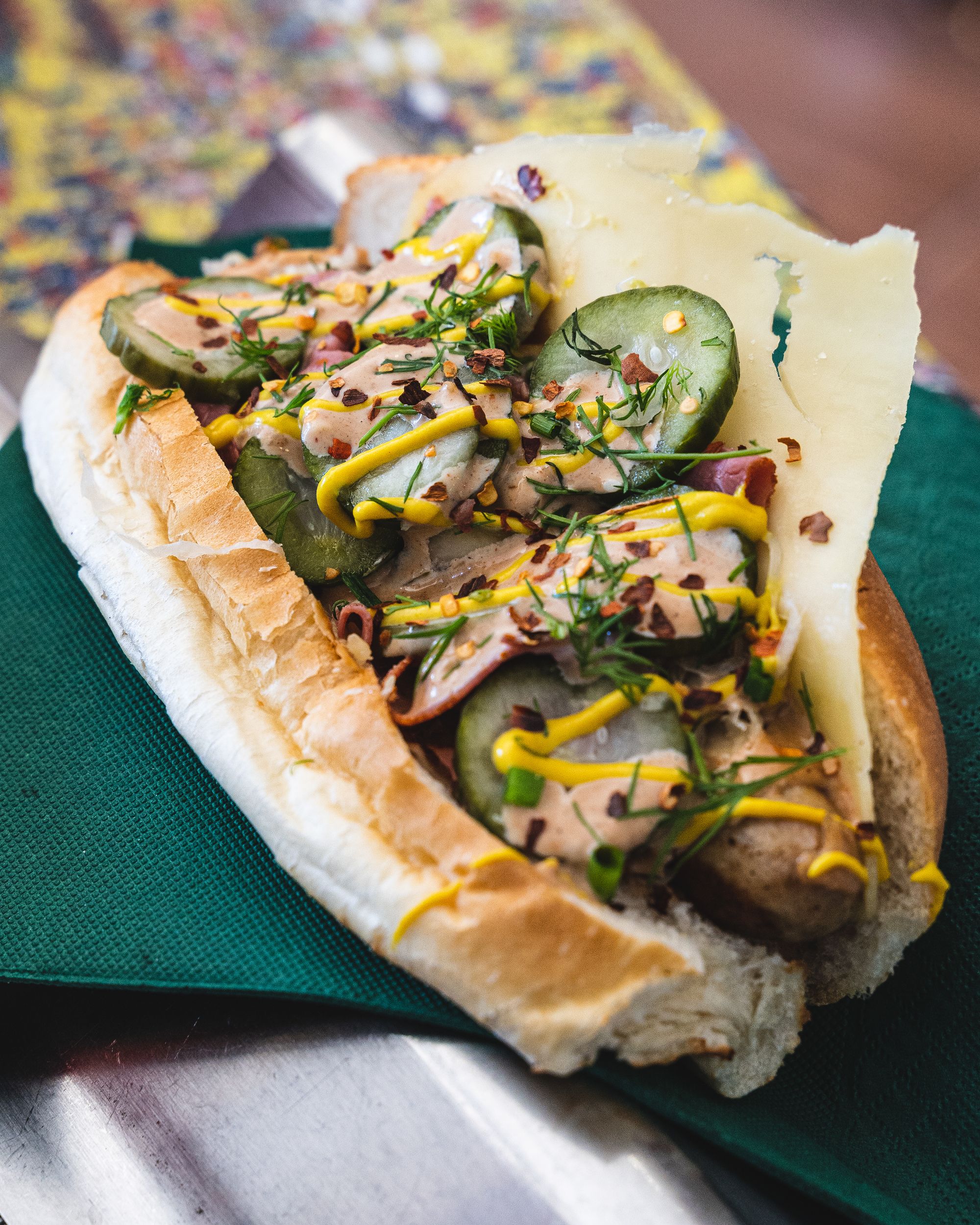 Hot dog with pickles, sauerkraut, mustard, chives and cheese