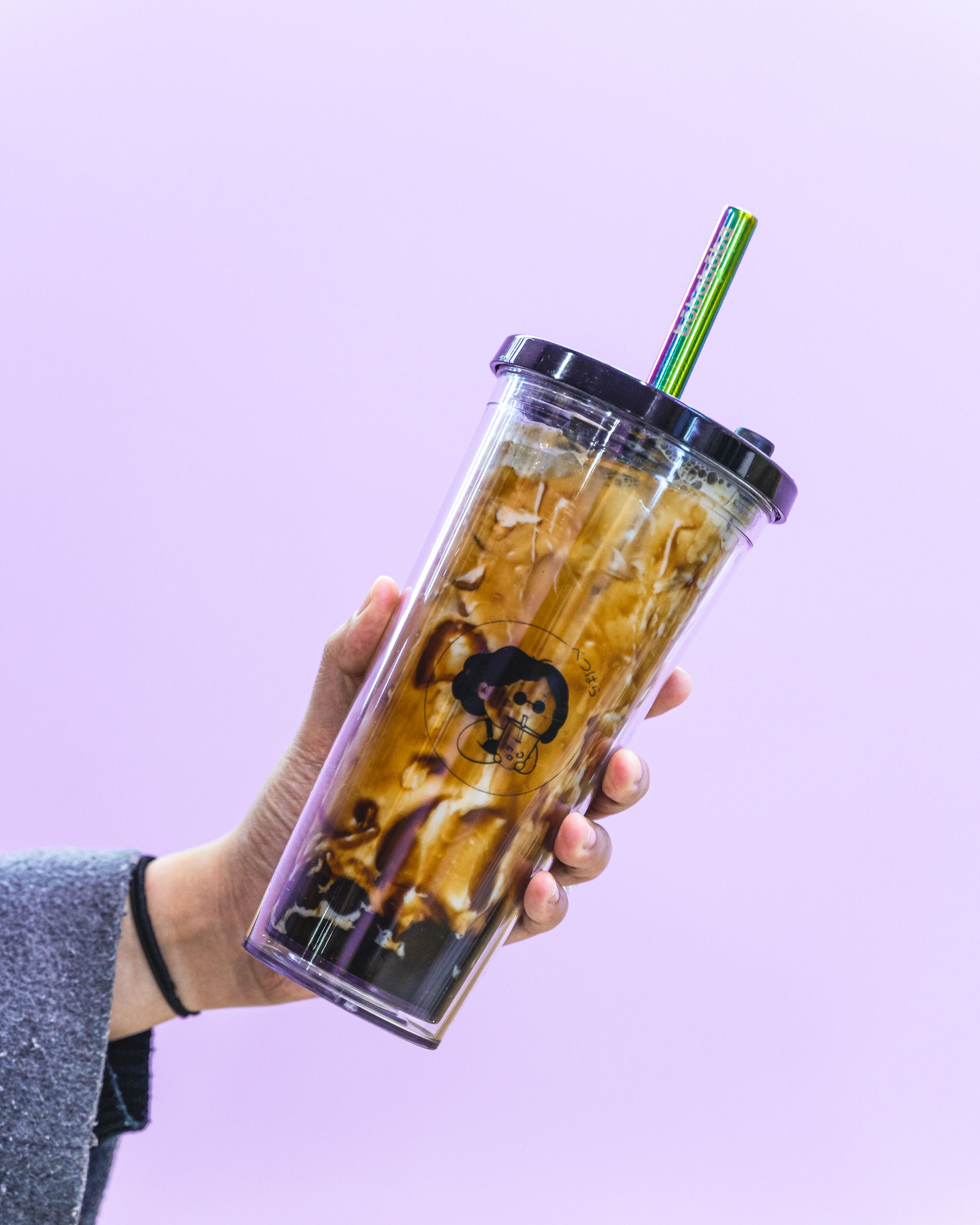 Hand holding a Bobaboba branded plastic bubble tea cup with brown sugar boba inside