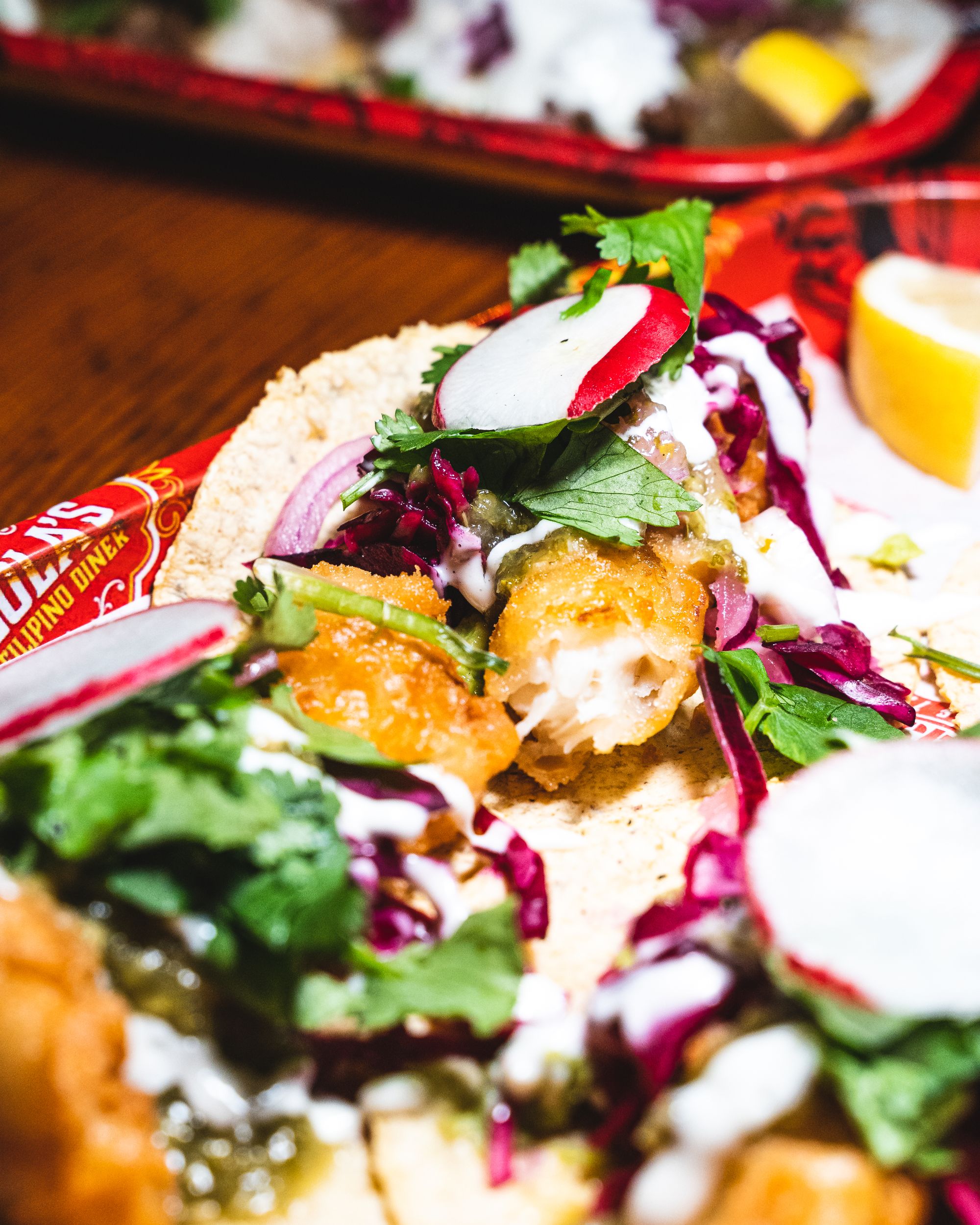 Close up of fish tacos with purple cabbage, coriander and guac