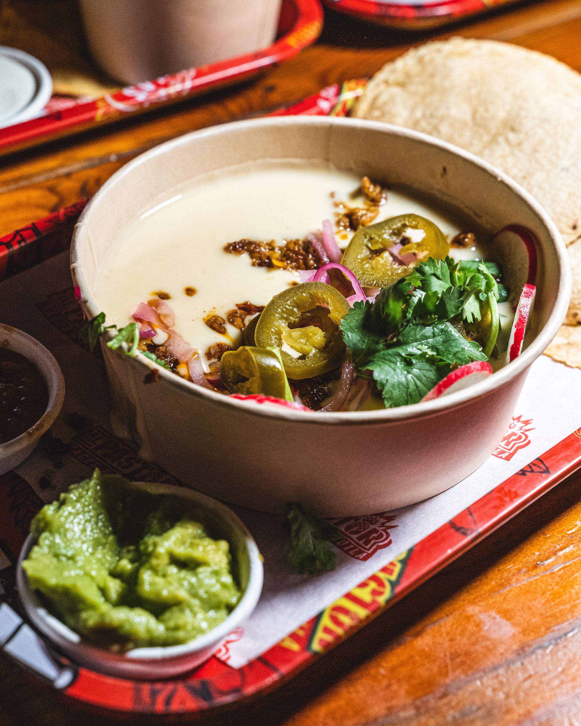 Close up of cheese in a paper bowl with chorizo, jalapeno and coriander