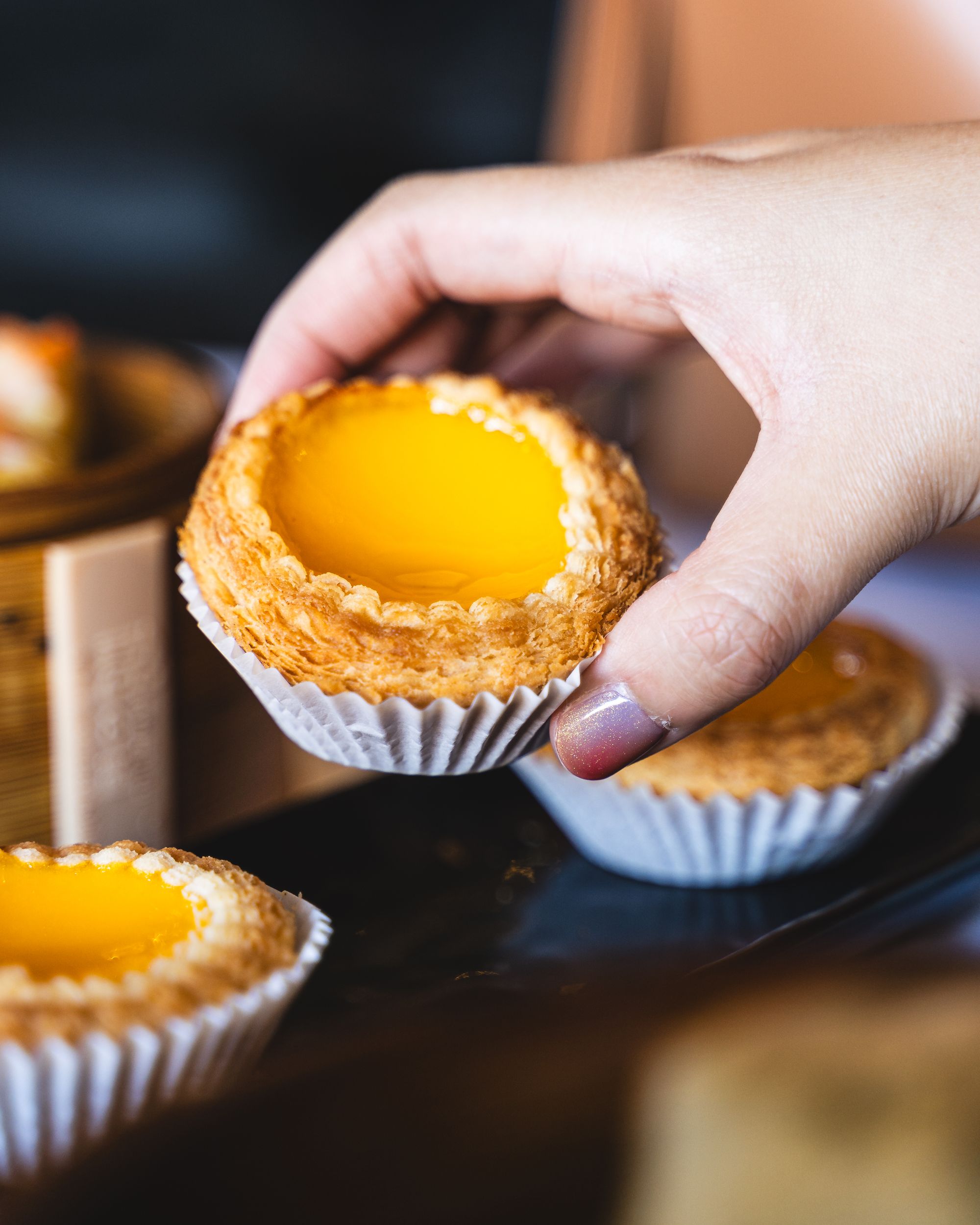 Manicured hand holding an egg tart