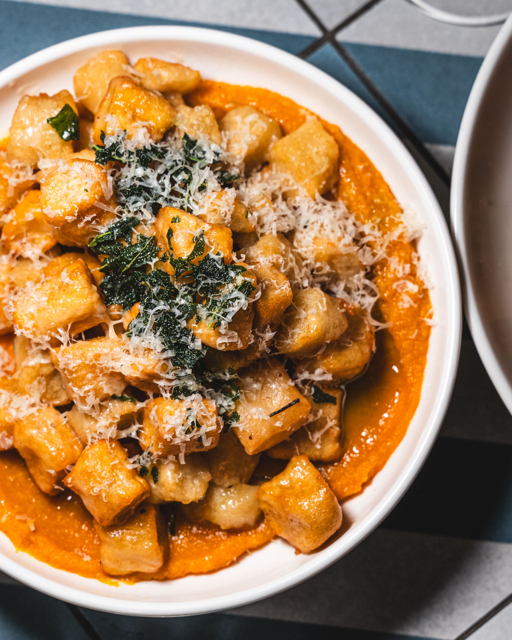 Top down shot of gnocchi with pumpkin puree, crispy kale and shaved cheese