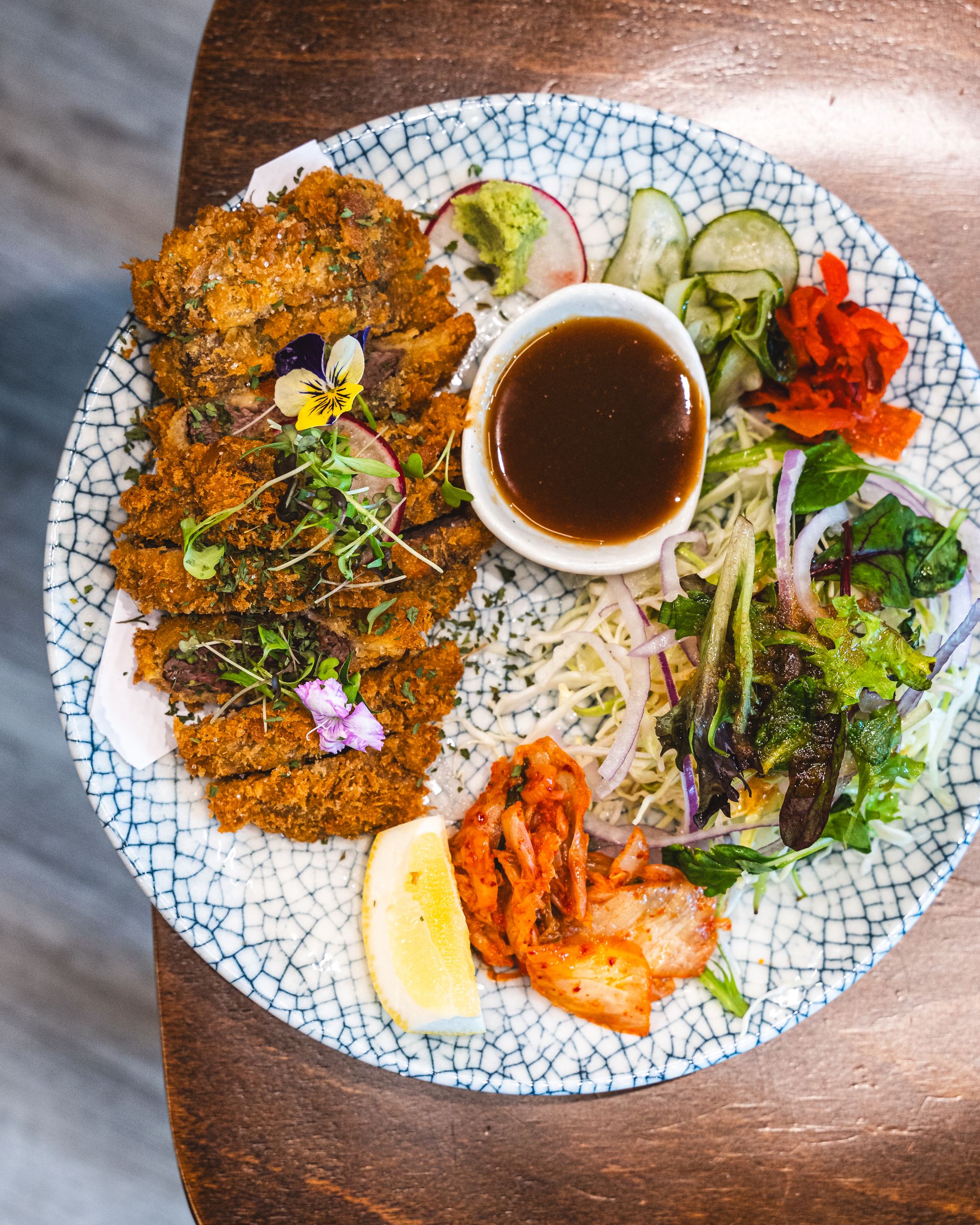 Top down shot of katsu and lemon, kimchi, salad