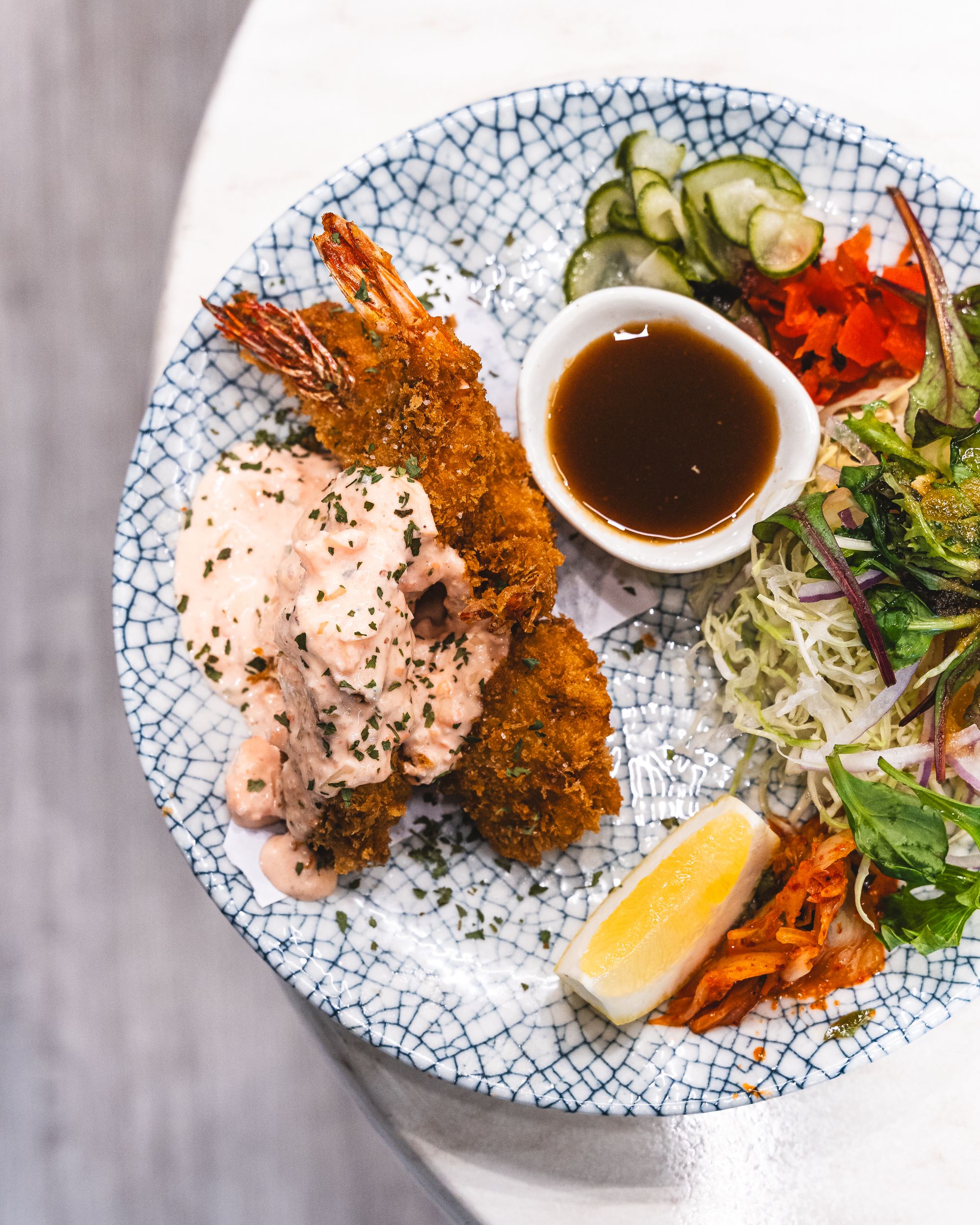 Top down shot of fried seafood and lemon, kimchi, salad